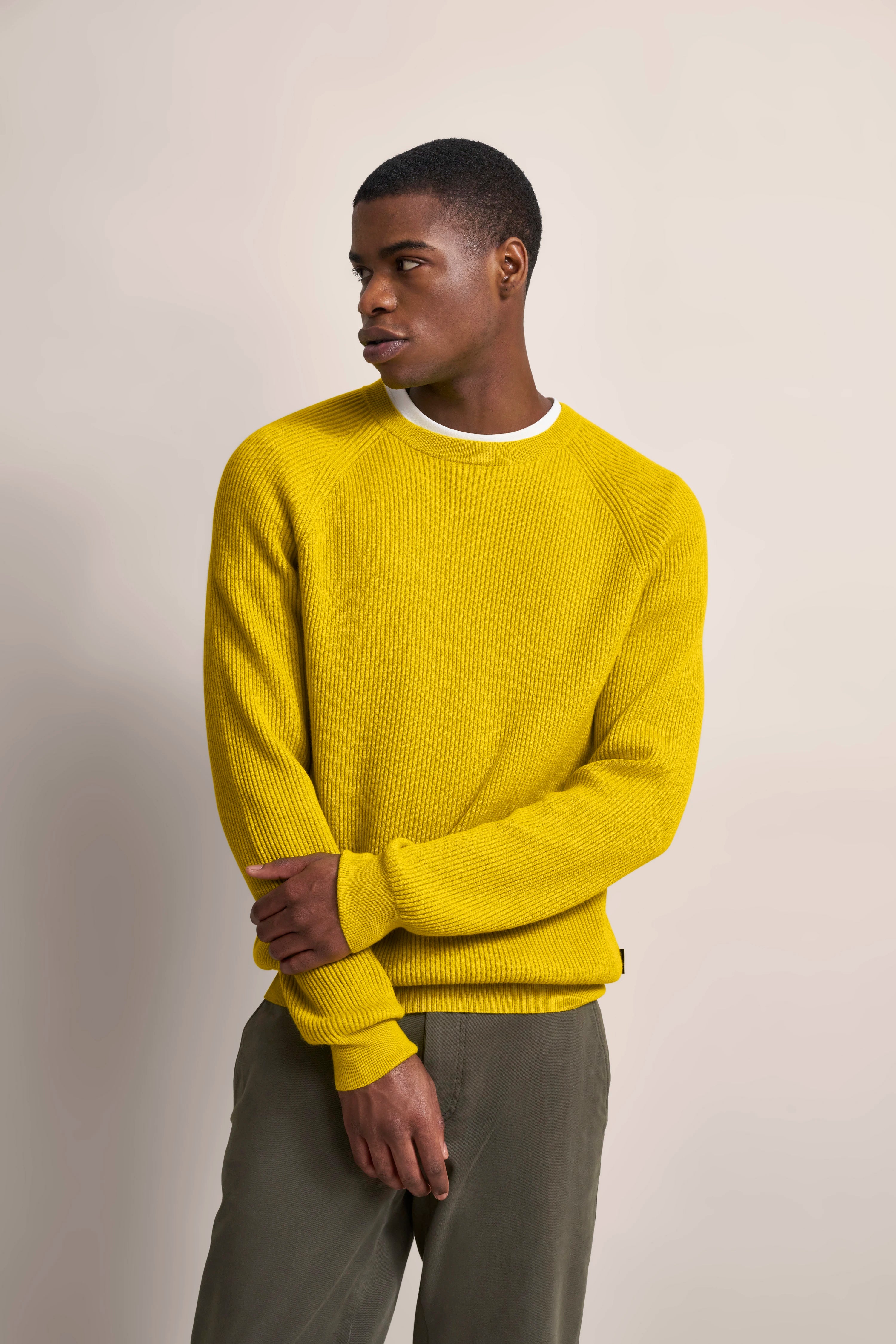 Gelber Pullover, legeres Modelbild, lässige Pose, bugatti Outfit für stilvolle Freizeitmode.