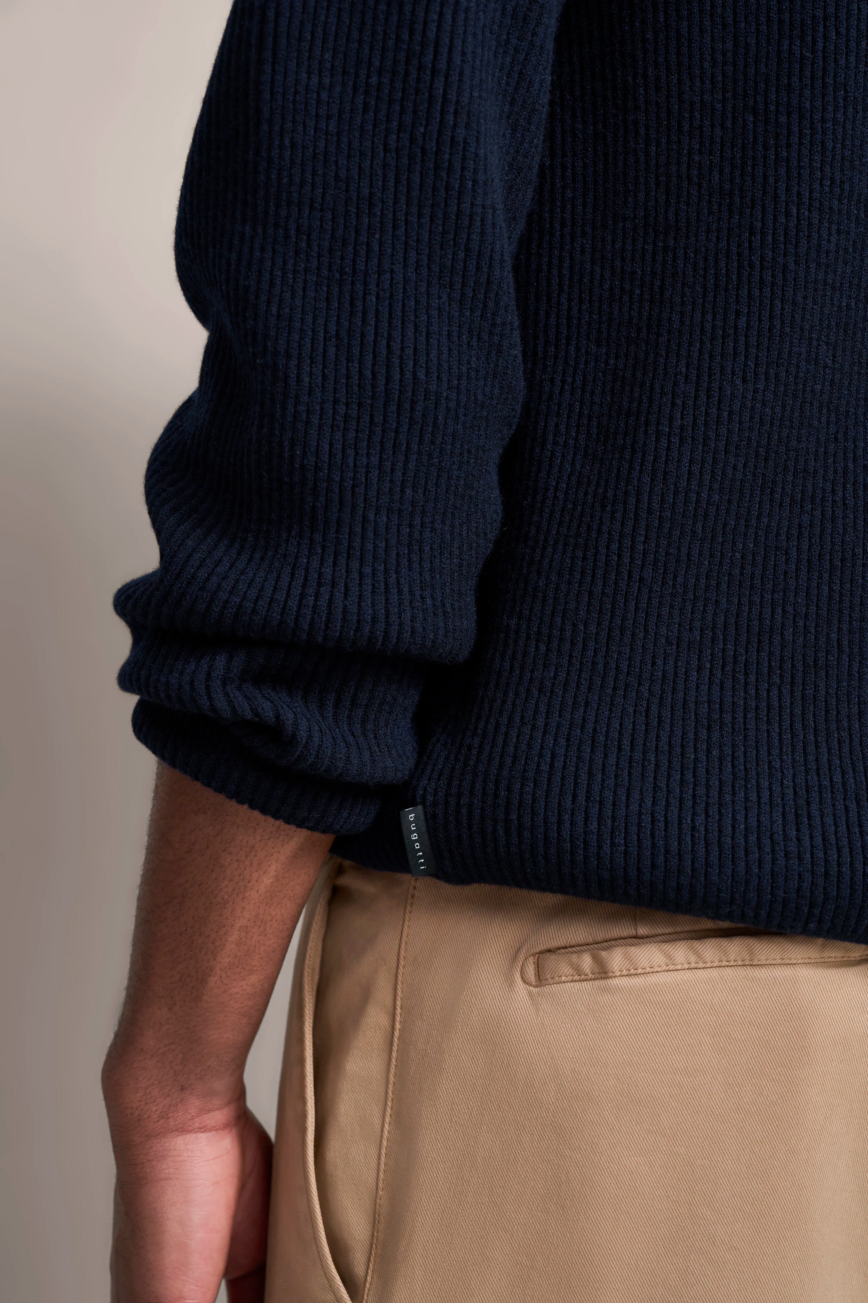 Dunkelblauer bugatti Pullover mit beigefarbener Hose, legeres Büstenbild.