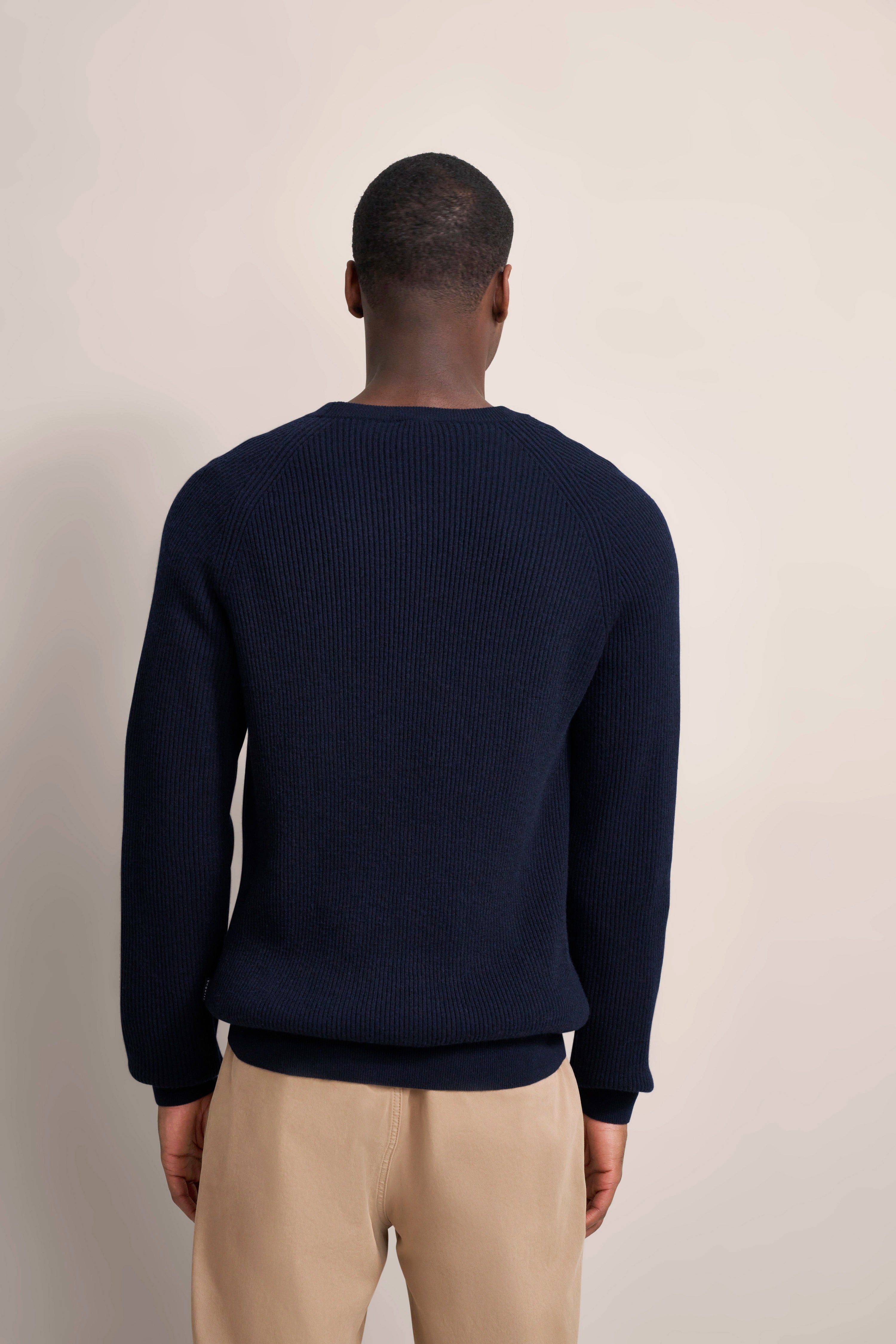 Dunkelblauer Pullover von bugatti, Model von hinten, Beige Hose, legeres Posing.