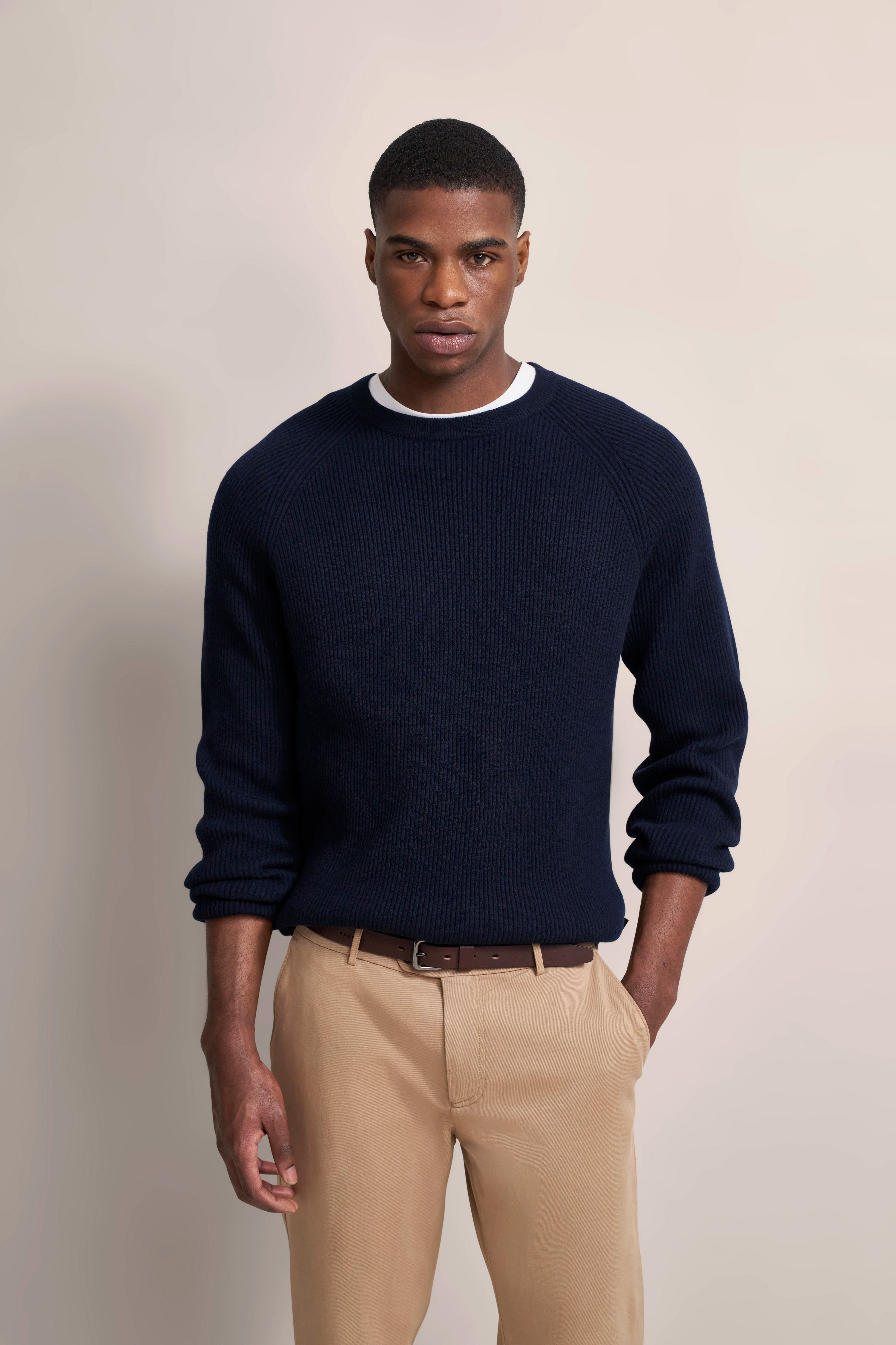 Modelbild: Navy Pullover, beige Chinos, legeres Posing. Eleganter, zeitloser Stil von bugatti.