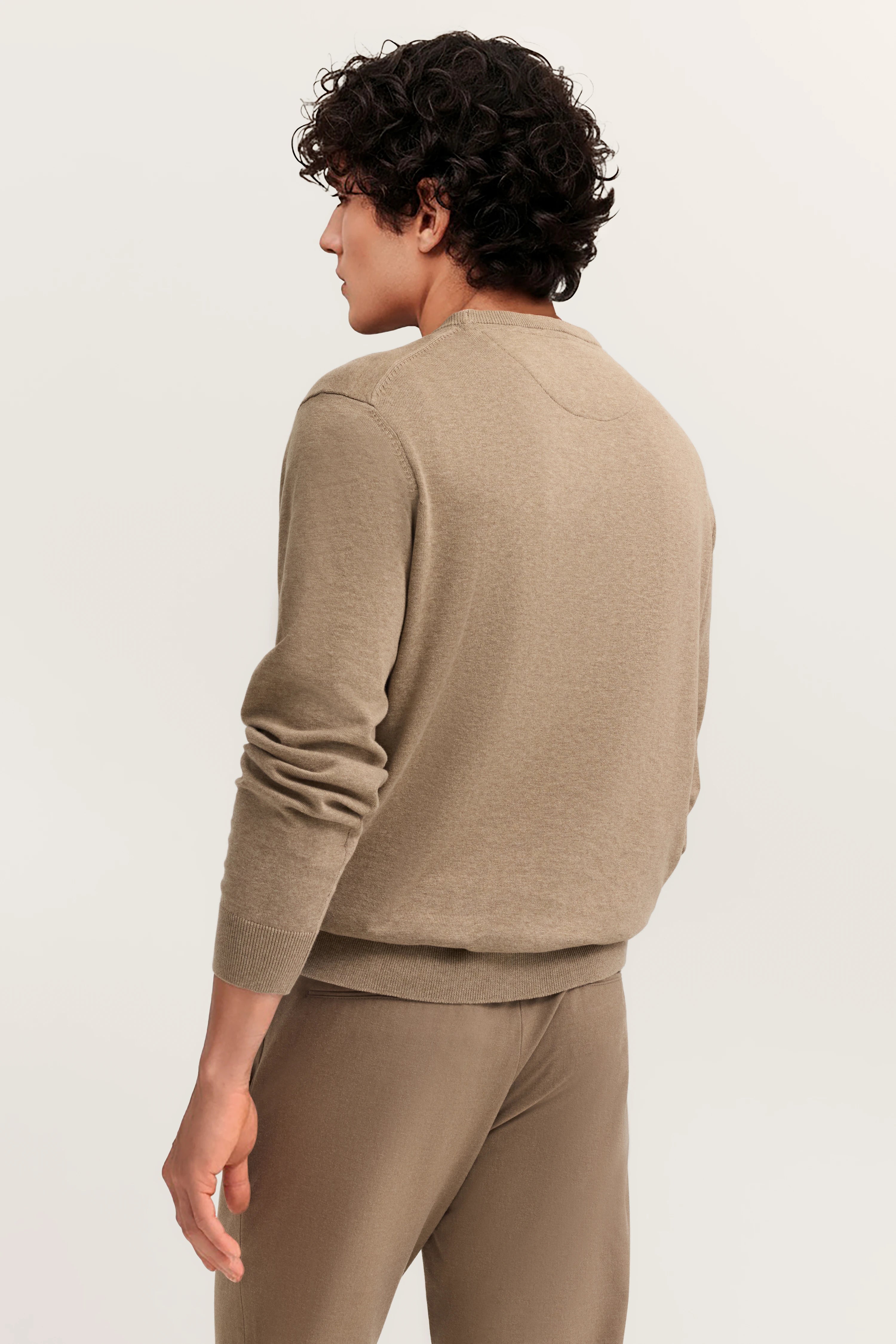 Beigefarbener bugatti Pullover und Hose, Seitenansicht Model, entspannte Pose.