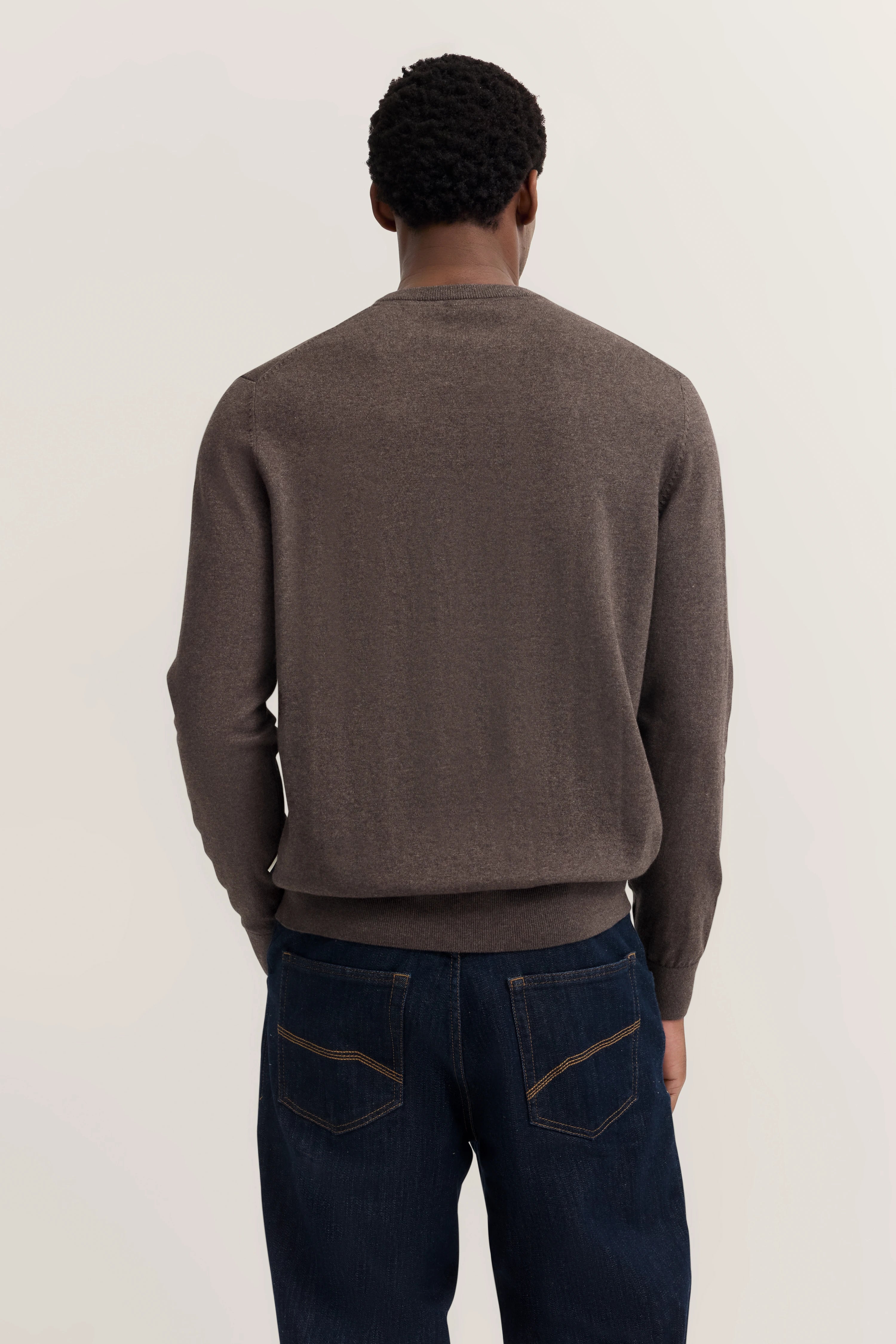 Bruine bugatti-trui, donkerblauwe jeans, model van achteren gezien.