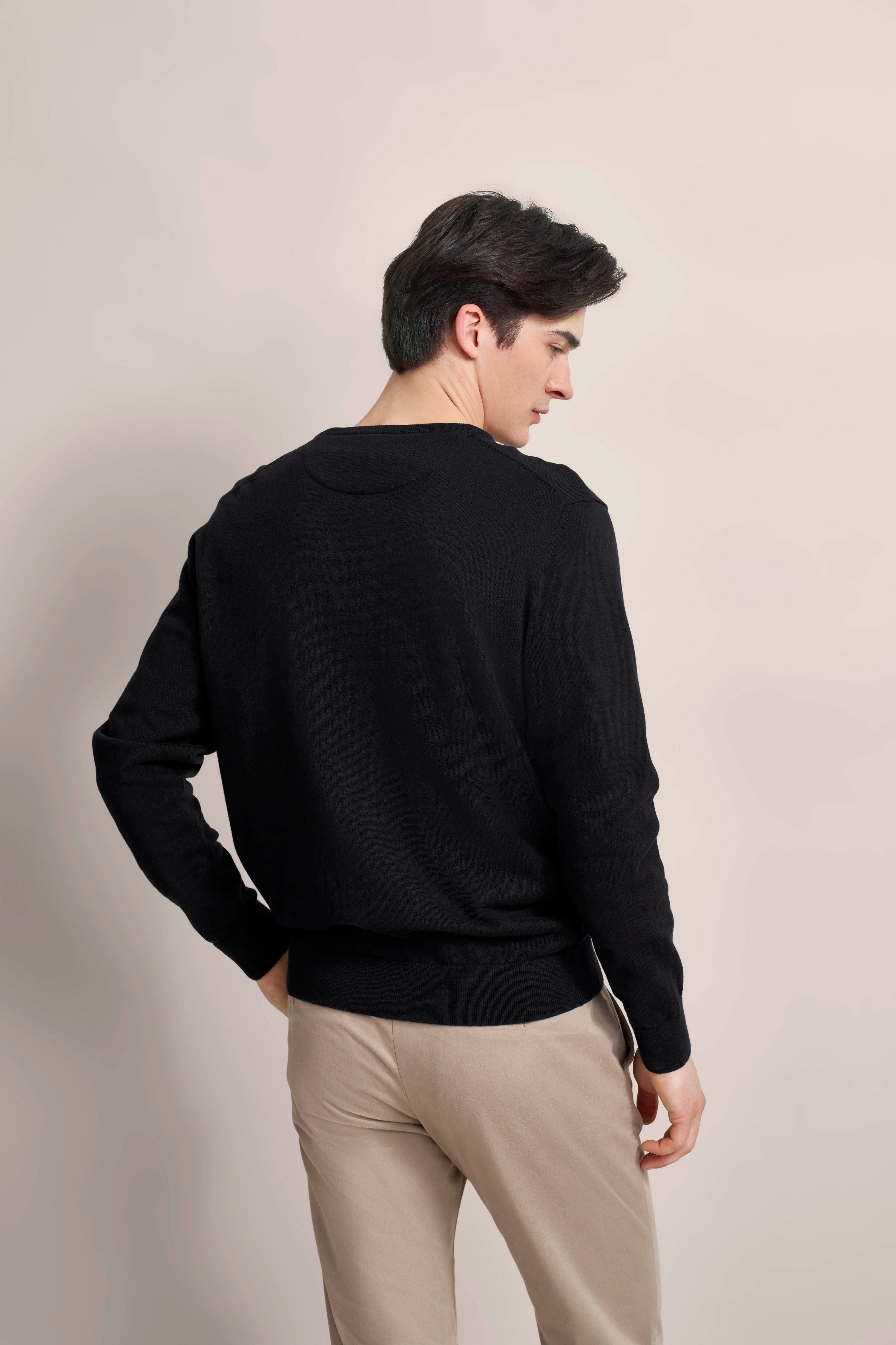 Schwarz-beiger Look mit bugatti Pullover, Model von hinten, entspanntes Posing.