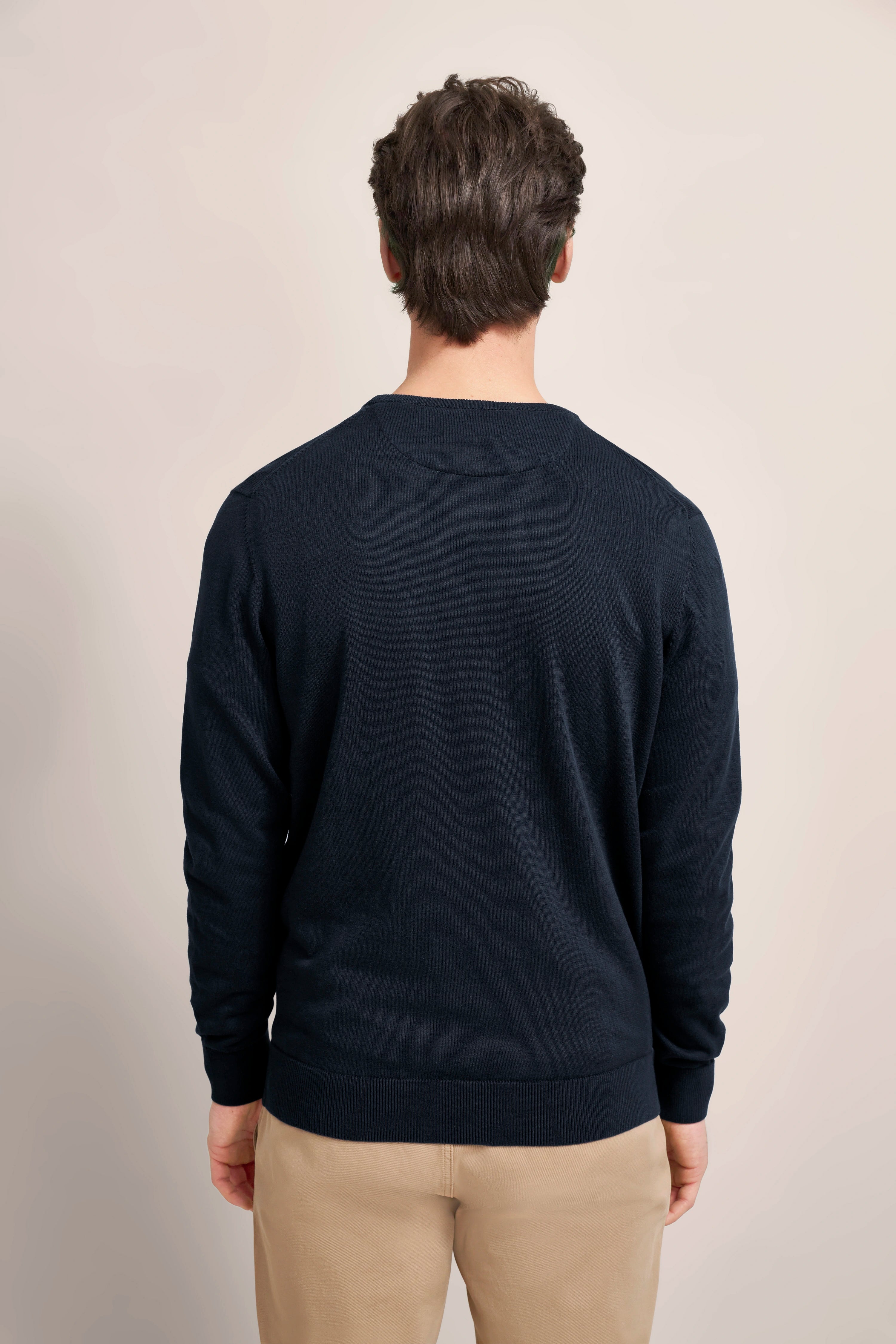 Navy Pullover von bugatti, Rückansicht, kombiniert mit beigen Hosen, Modelbild entspannte Haltung.