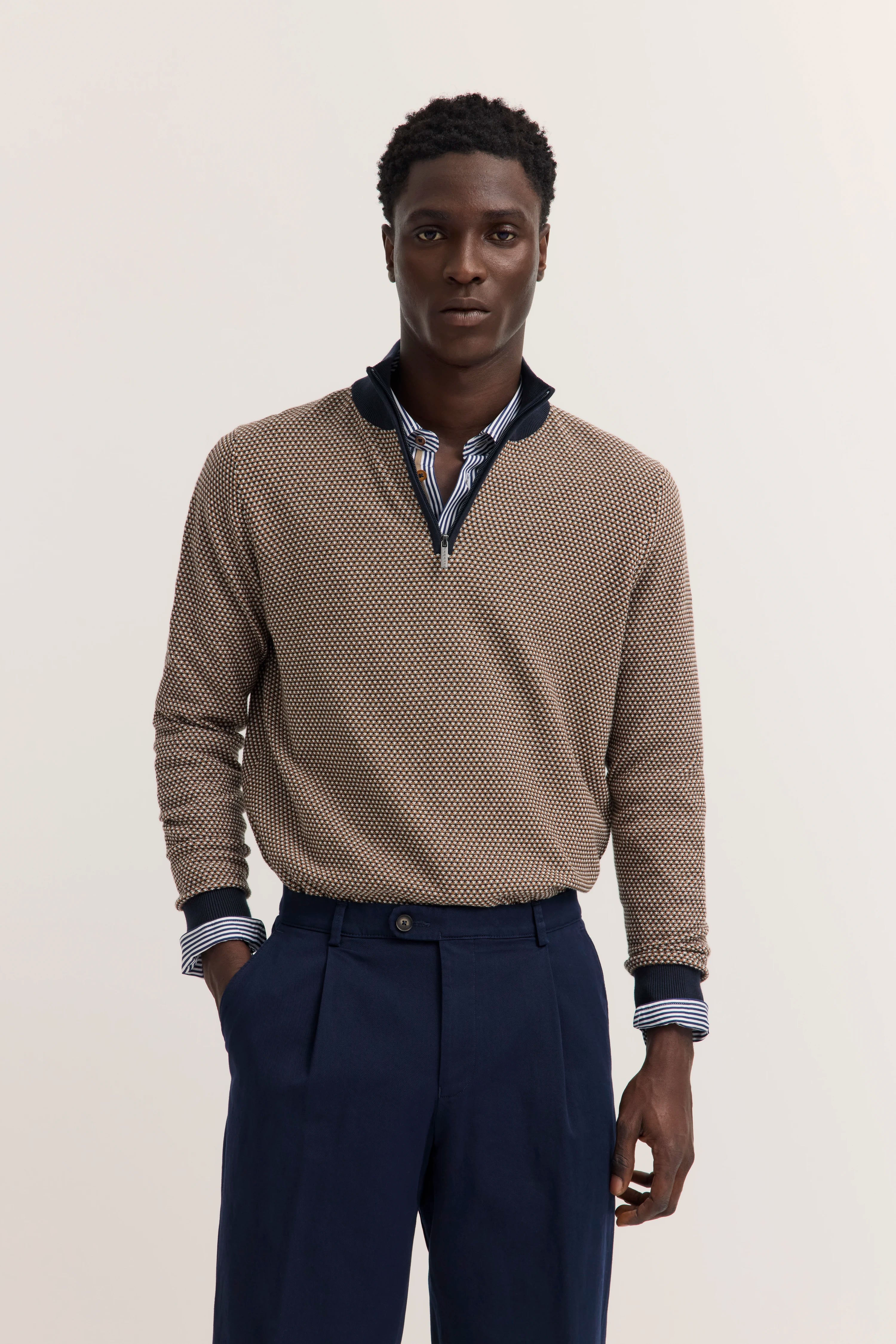 Modell in gemustertem Pullover und blauer Hose, lässige Pose, bugatti Stil.