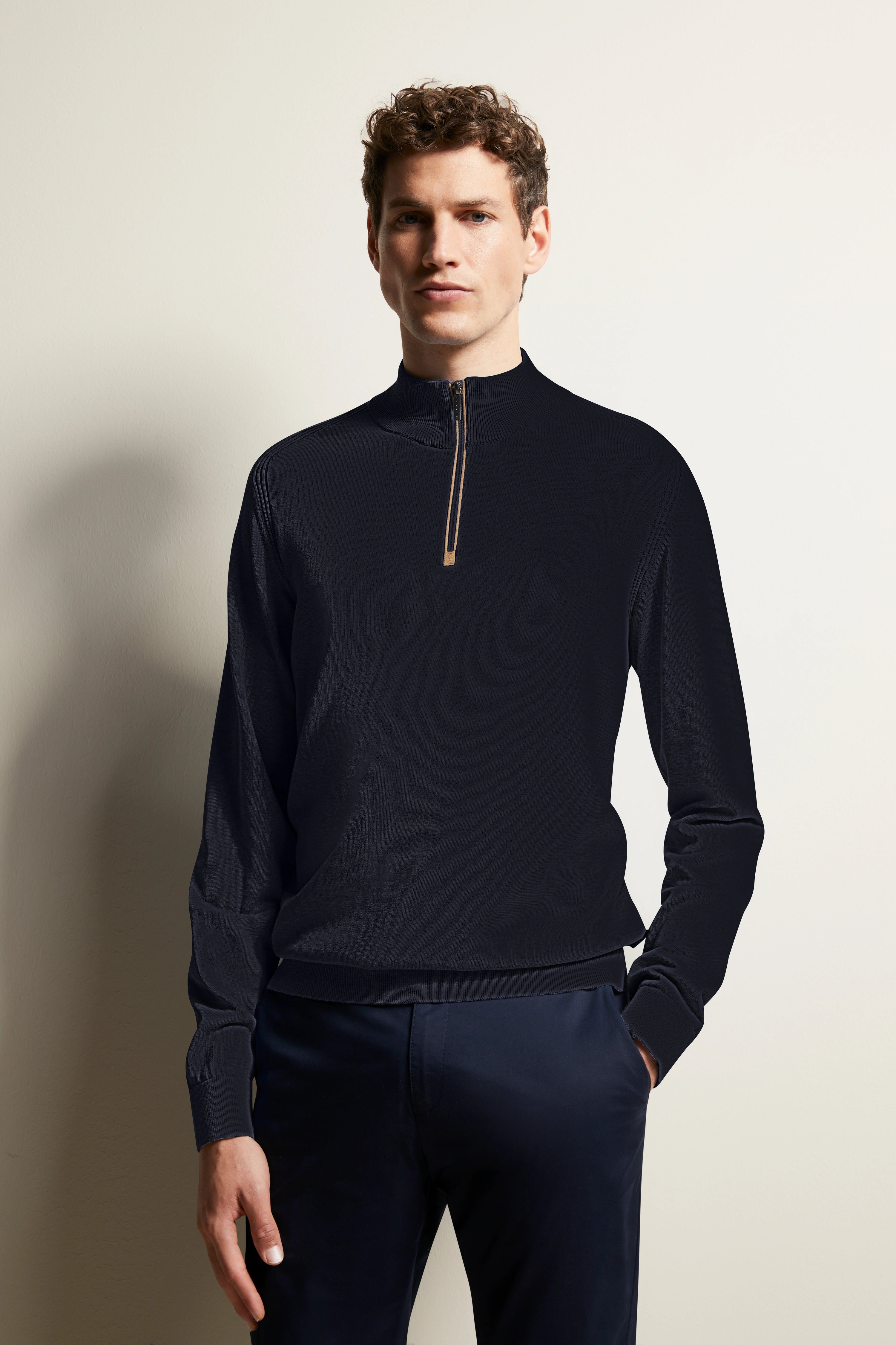 Model in navy bugatti Pullover mit Stehkragen und Reißverschluss, Hände in Taschen, legeres Posing.