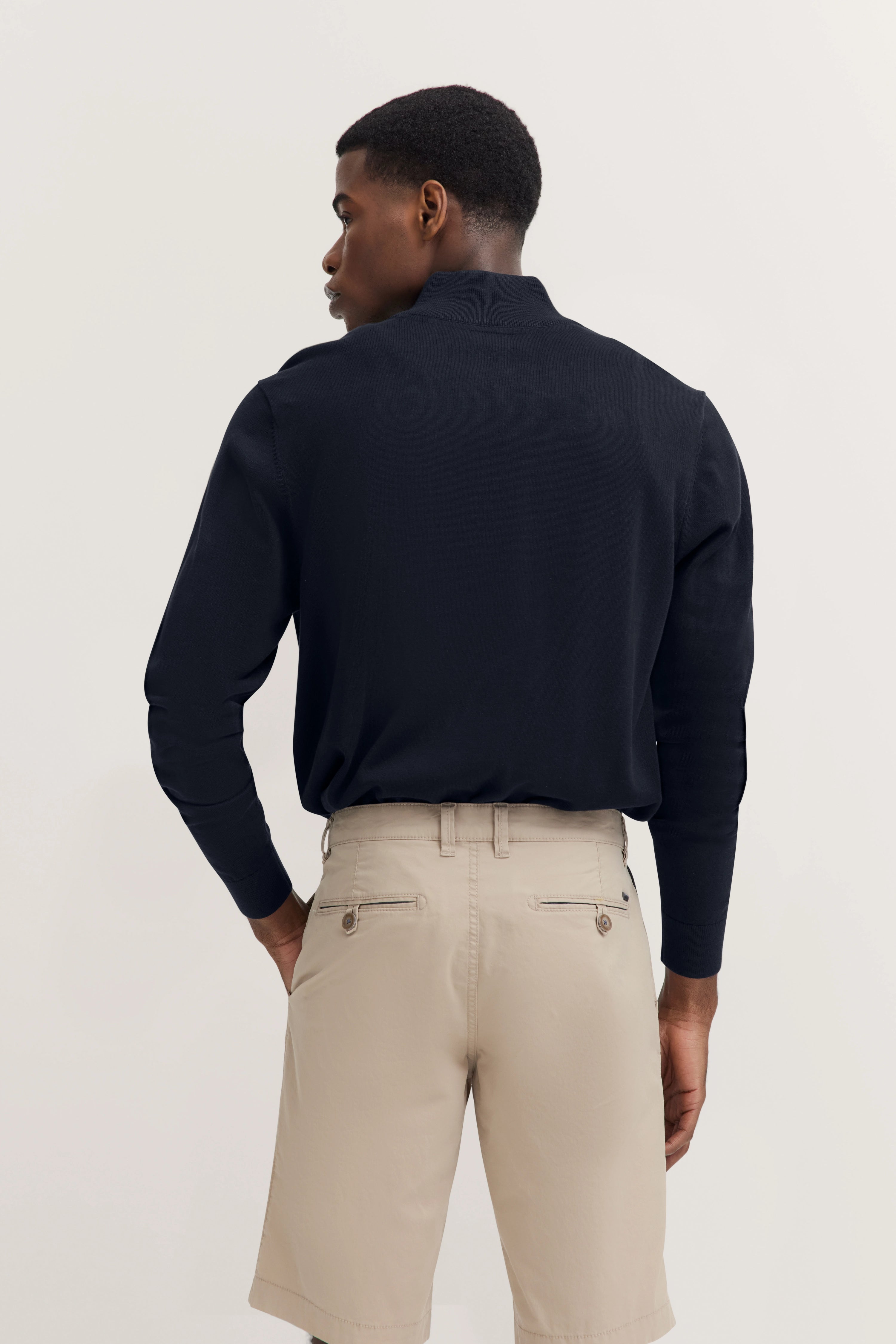 Marineblauwe pullover en beige shorts, achteraanzicht, casual modelbeeld, ontspannen pose.