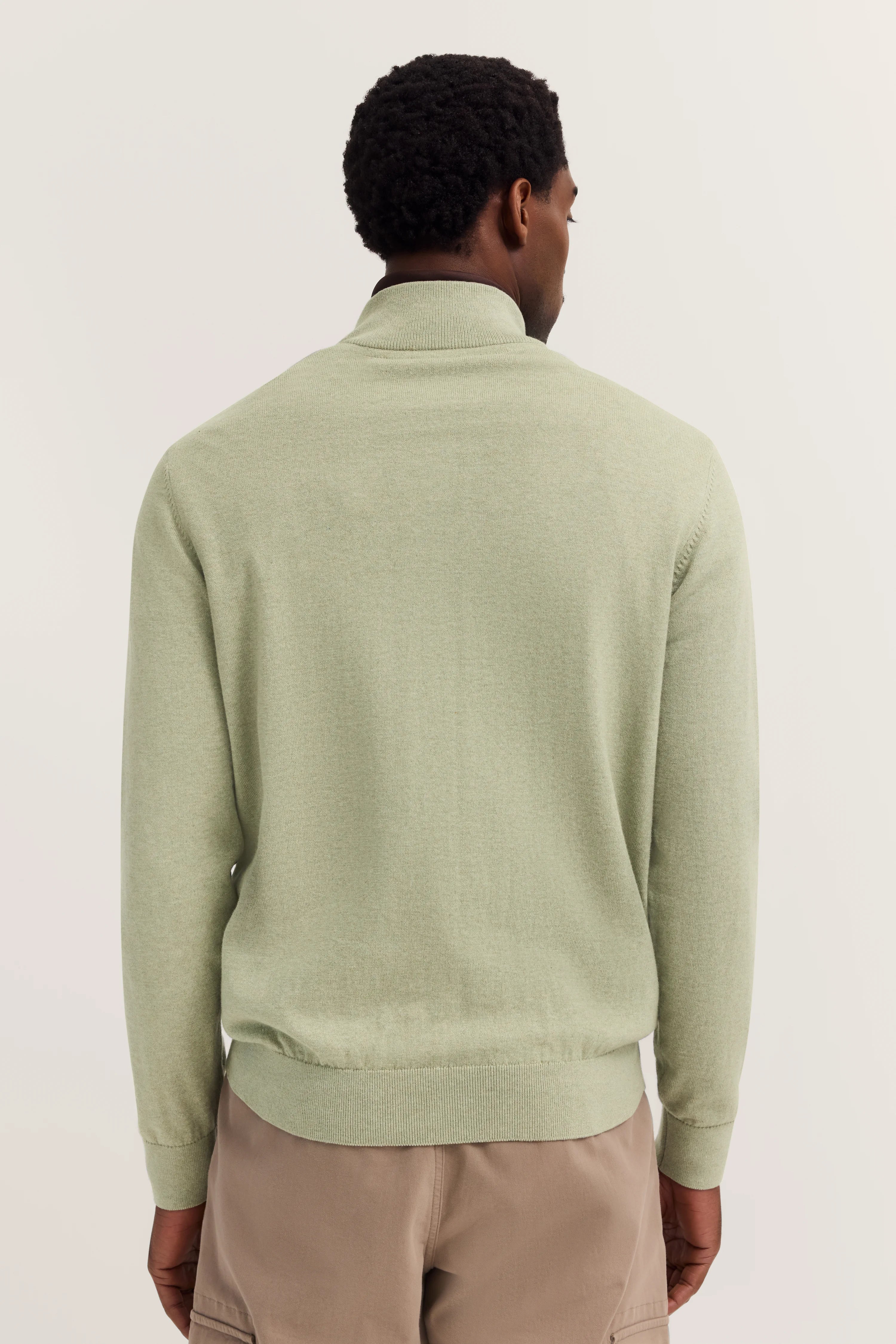 bugatti casual model, groene trui met opstaande kraag, beige broek, van achteren gefotografeerd.