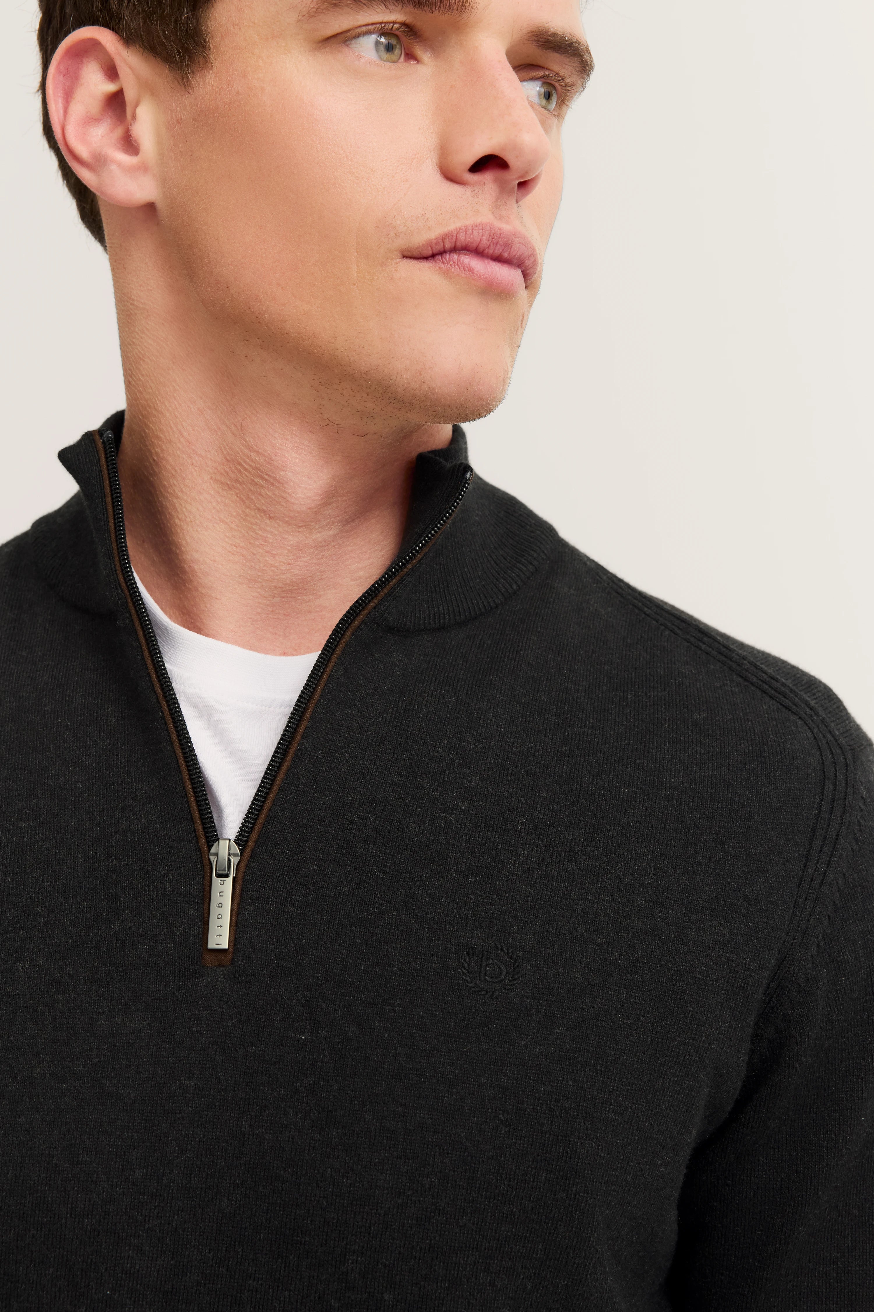 Schwarzer bugatti Pullover mit Reißverschluss, Modelbild, legeres Posing, weißes Shirt darunter.