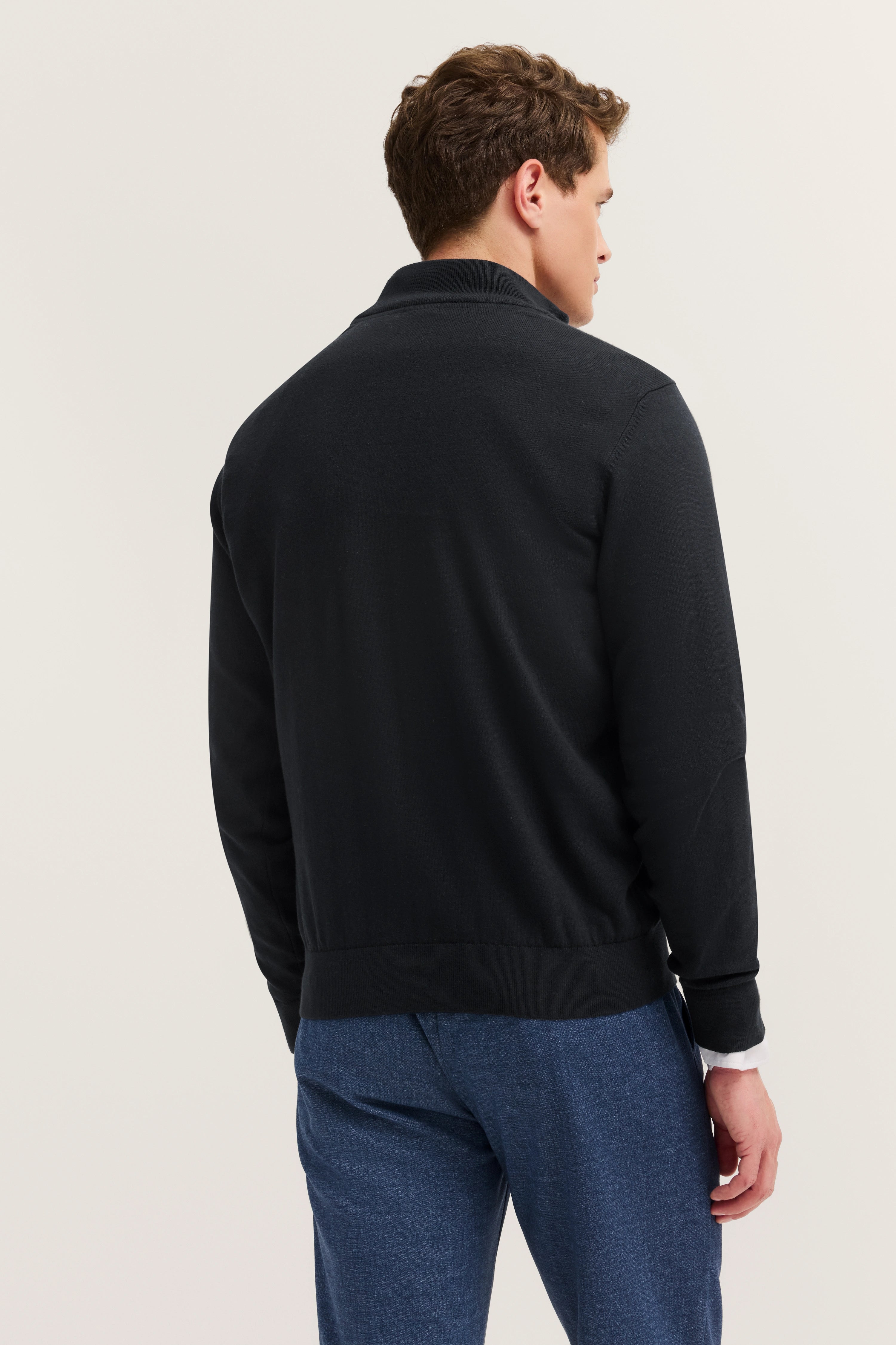 "Herren-Model in schwarzem Pullover, blauer Hose, Rückenansicht, legeres Posing, bugatti."