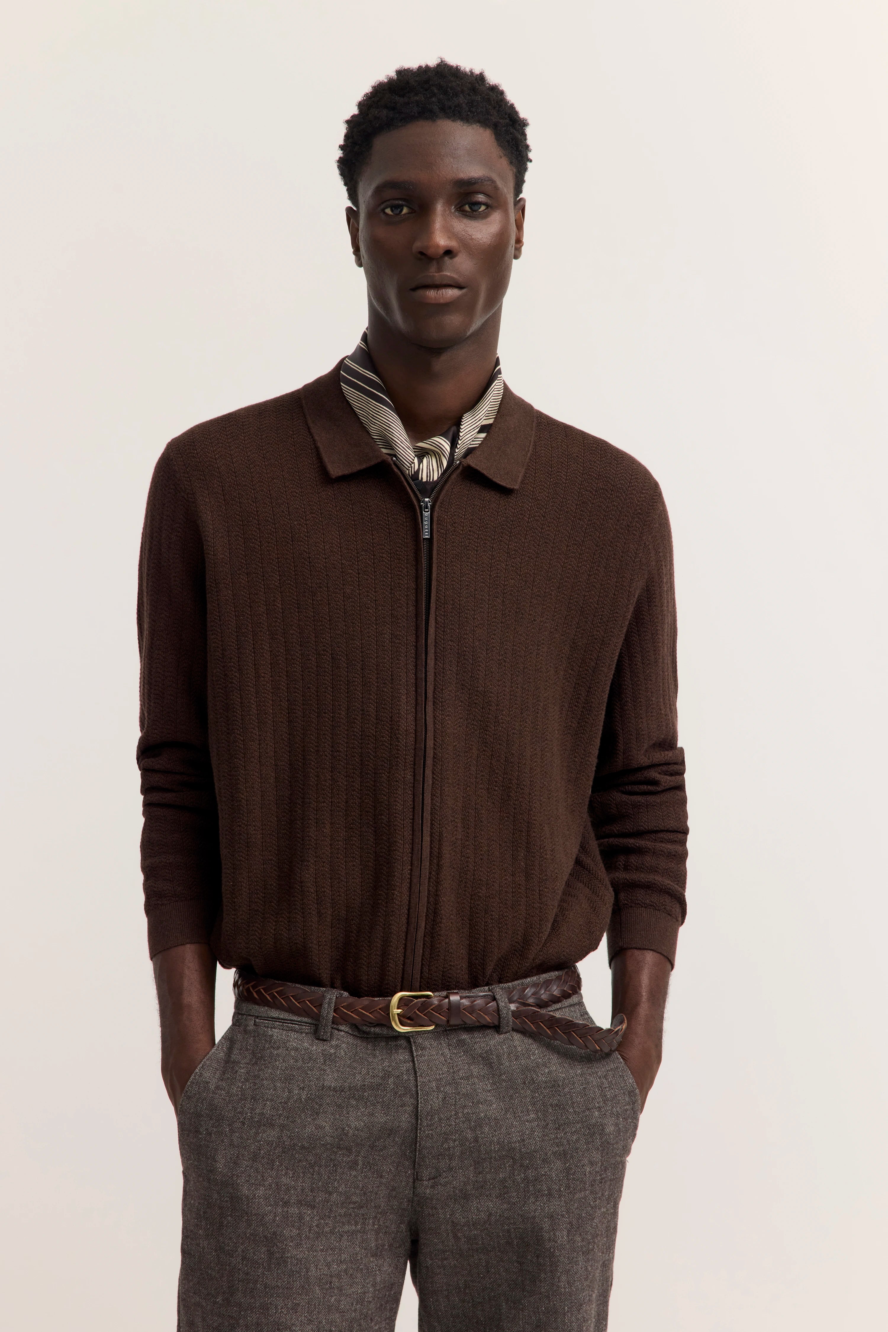 Brauner Strickpullover, gestreiftes Hemd, graue Hose, brauner Gürtel