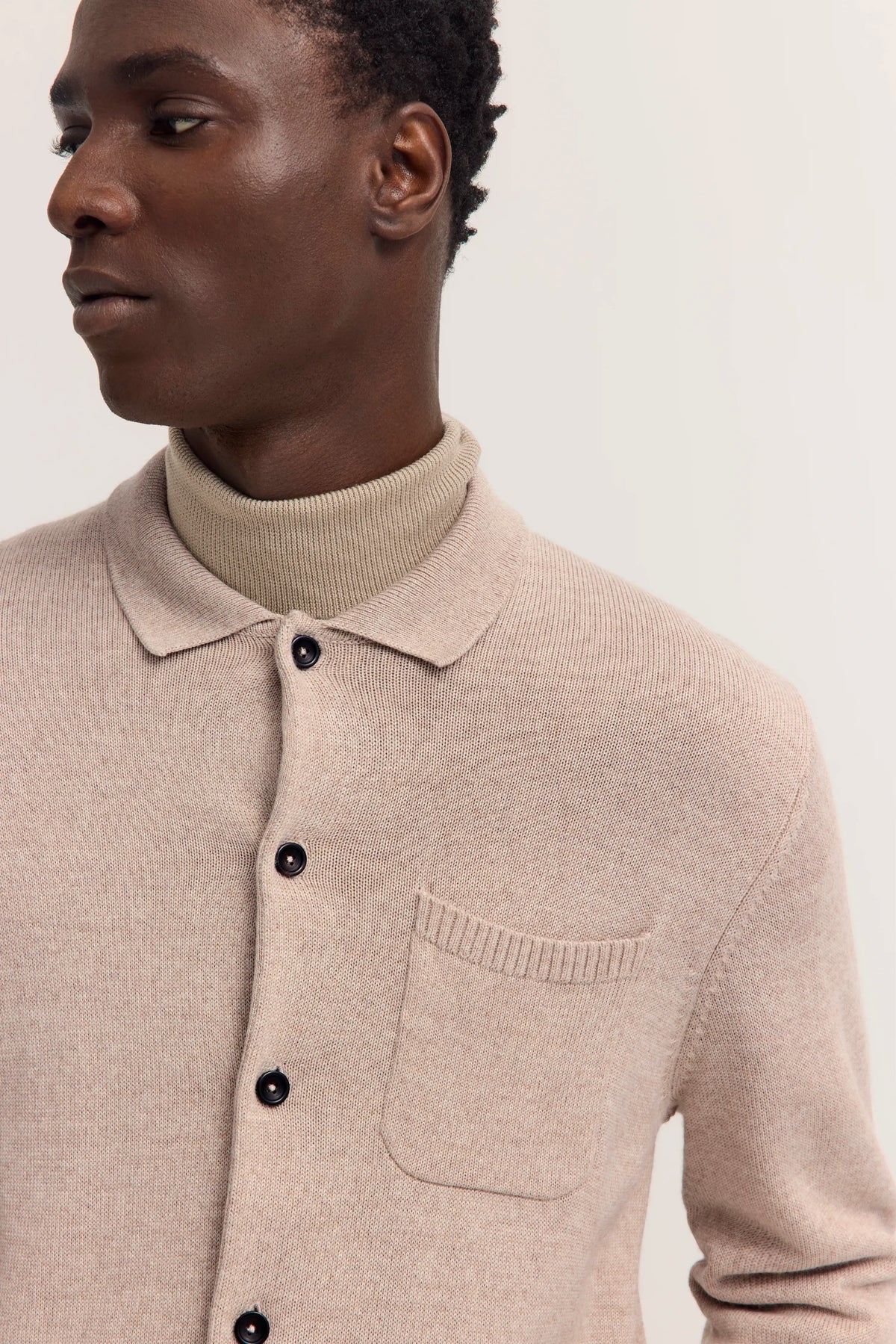 Beige Strickjacke von bugatti über beige Rollkragenpullover, Modelbild im Profil.