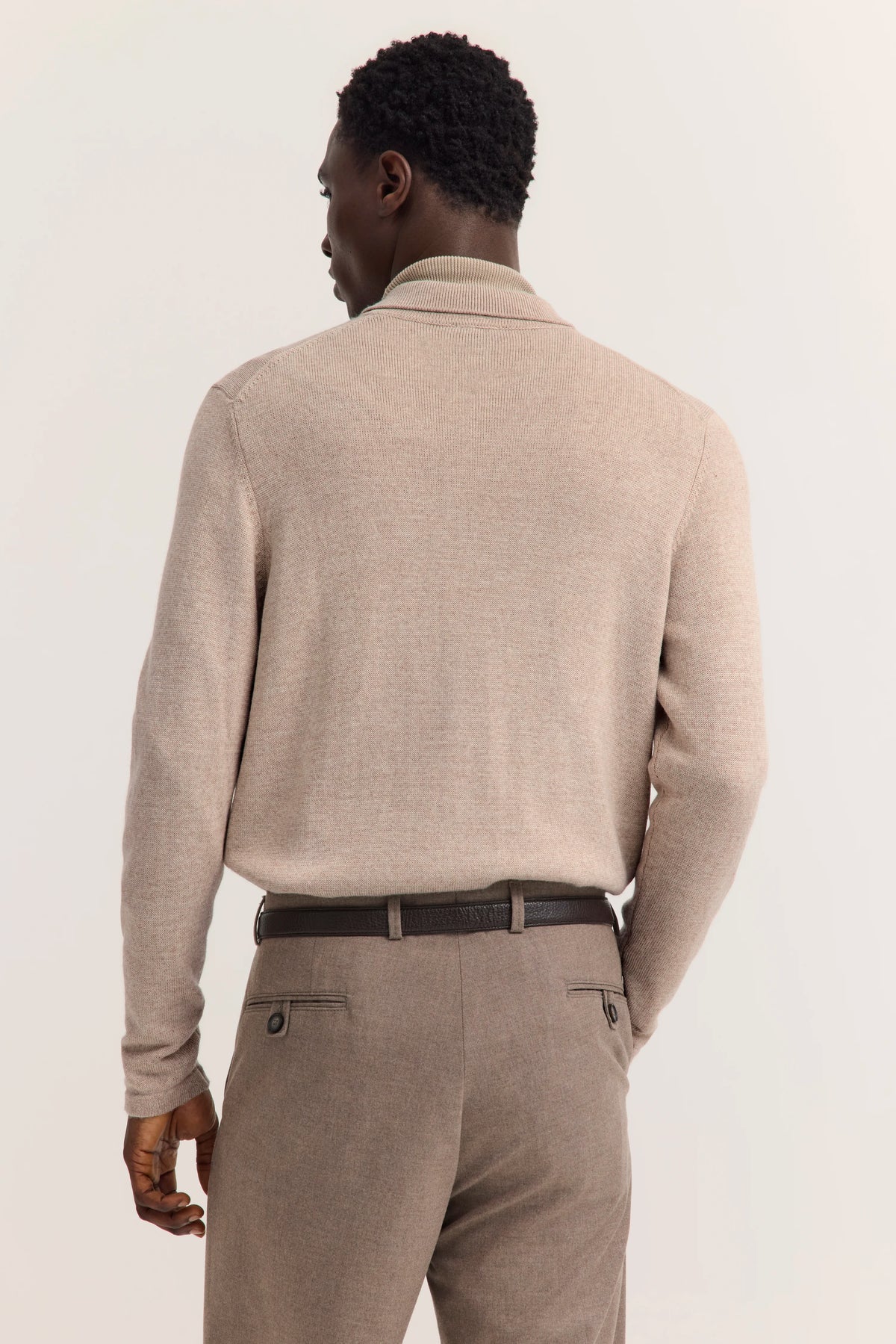 Bugatti Modelbild zeigt beige Pullover und Hose von hinten, lässige Pose.