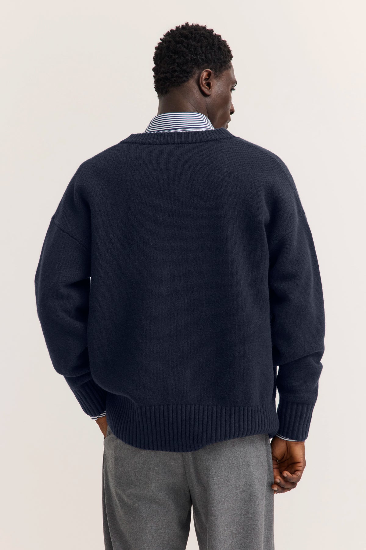 Navy Pullover und graue Hose, Modelbild, Rückenansicht.