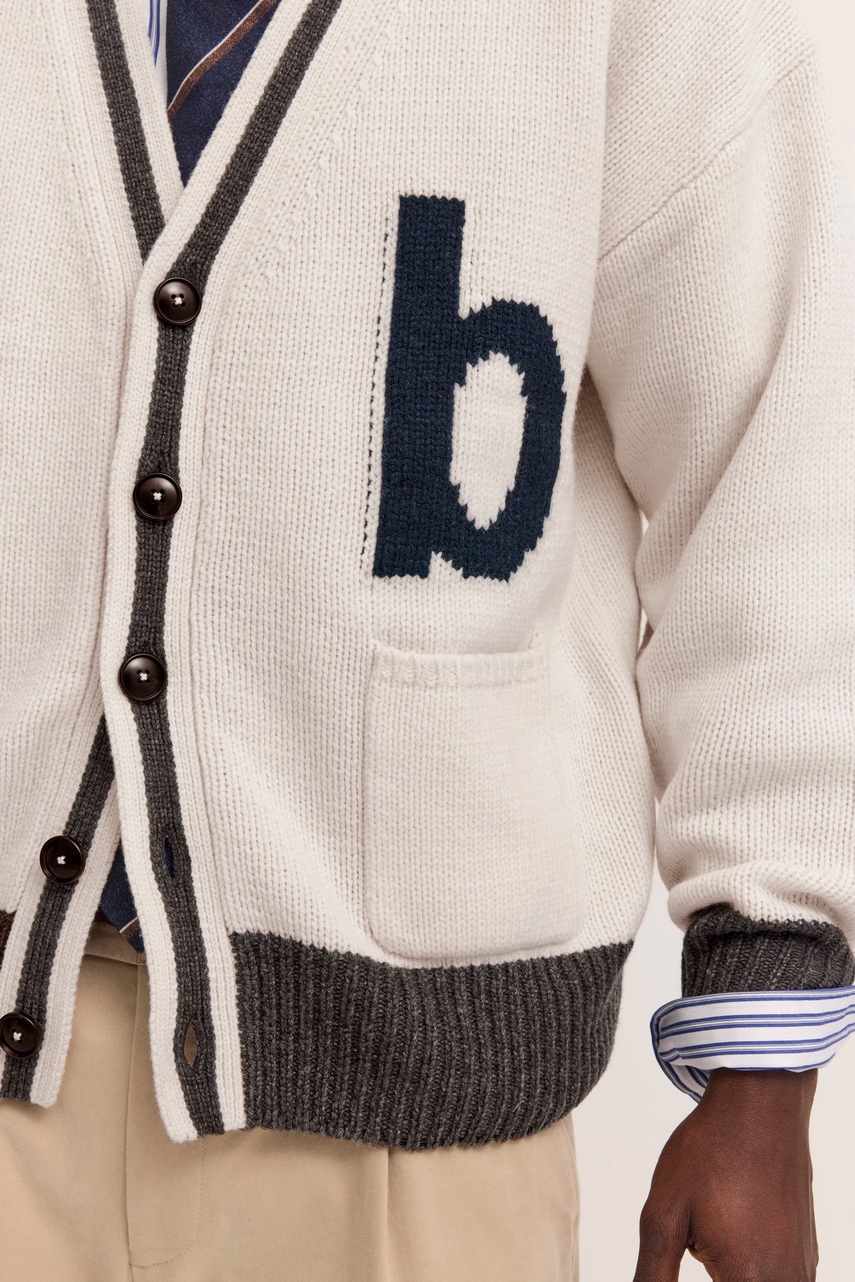 Weiße Strickjacke mit grauen Akzenten und "b"-Logo von bugatti, leger getragen.