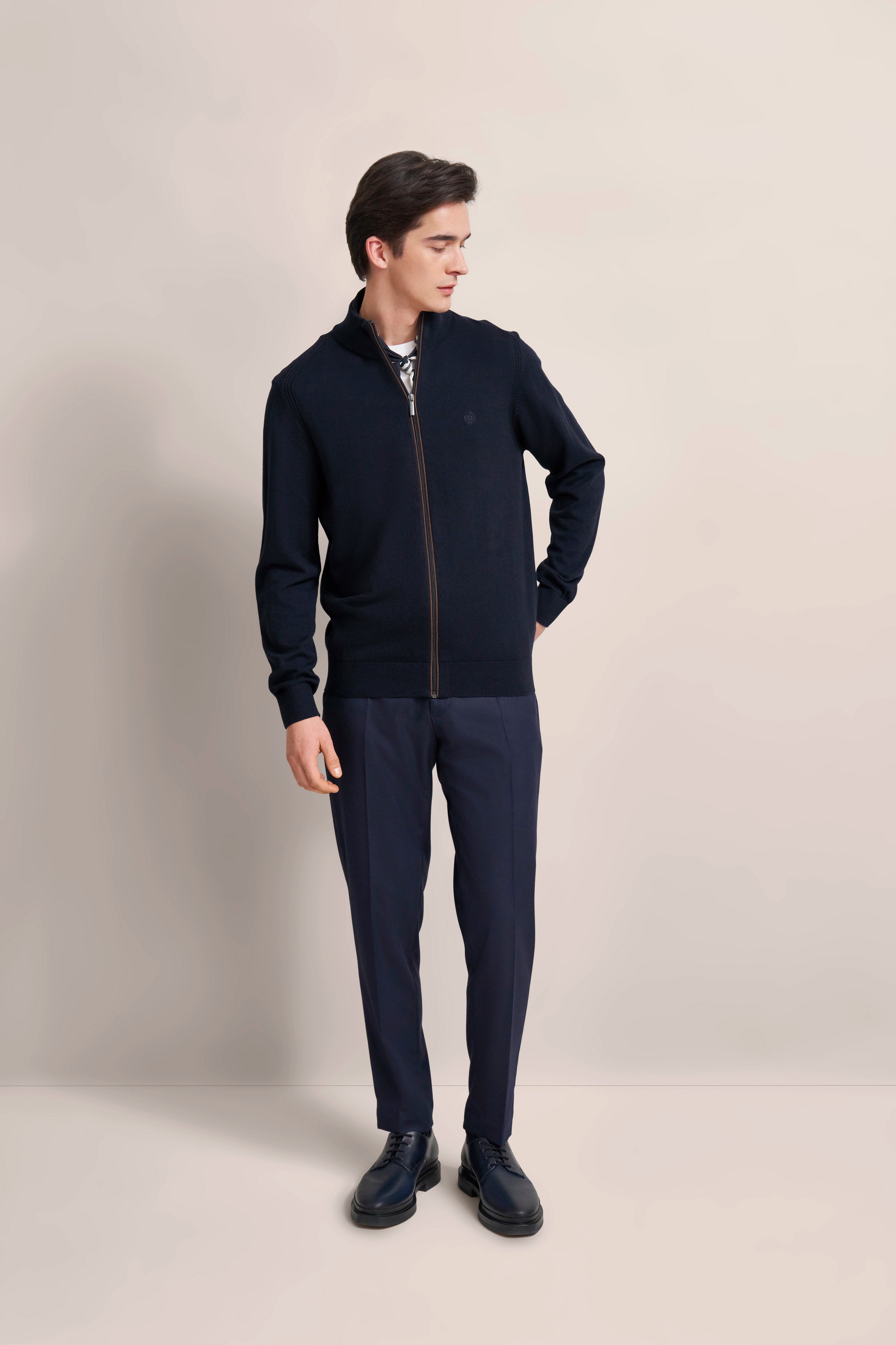 Model in navy bugatti Outfit mit Jacke und Hose, legeres Posing, entspannte Haltung.
