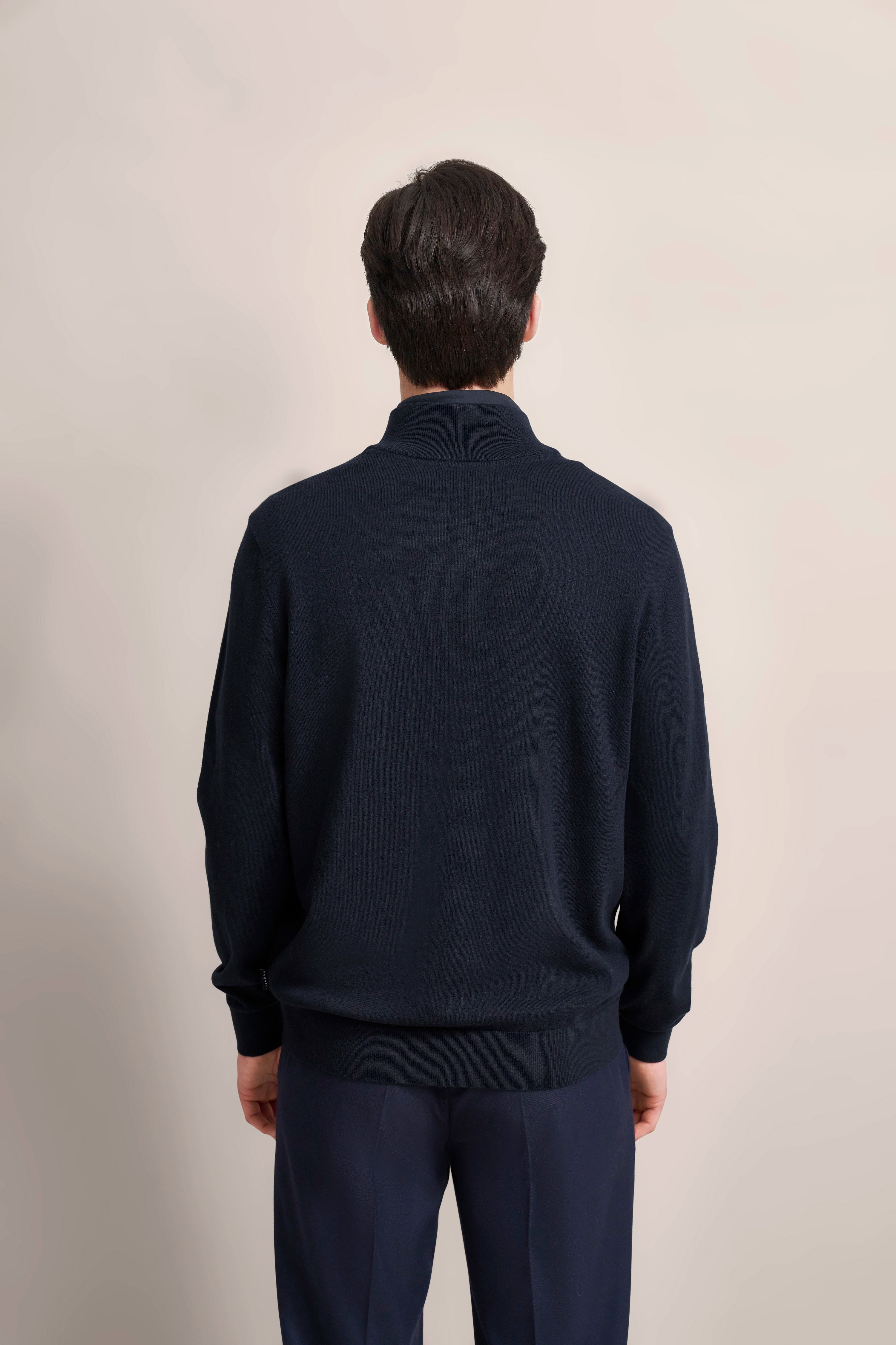 bugatti Model in dunkelblauem Pullover, Rückansicht, legeres Outfit.