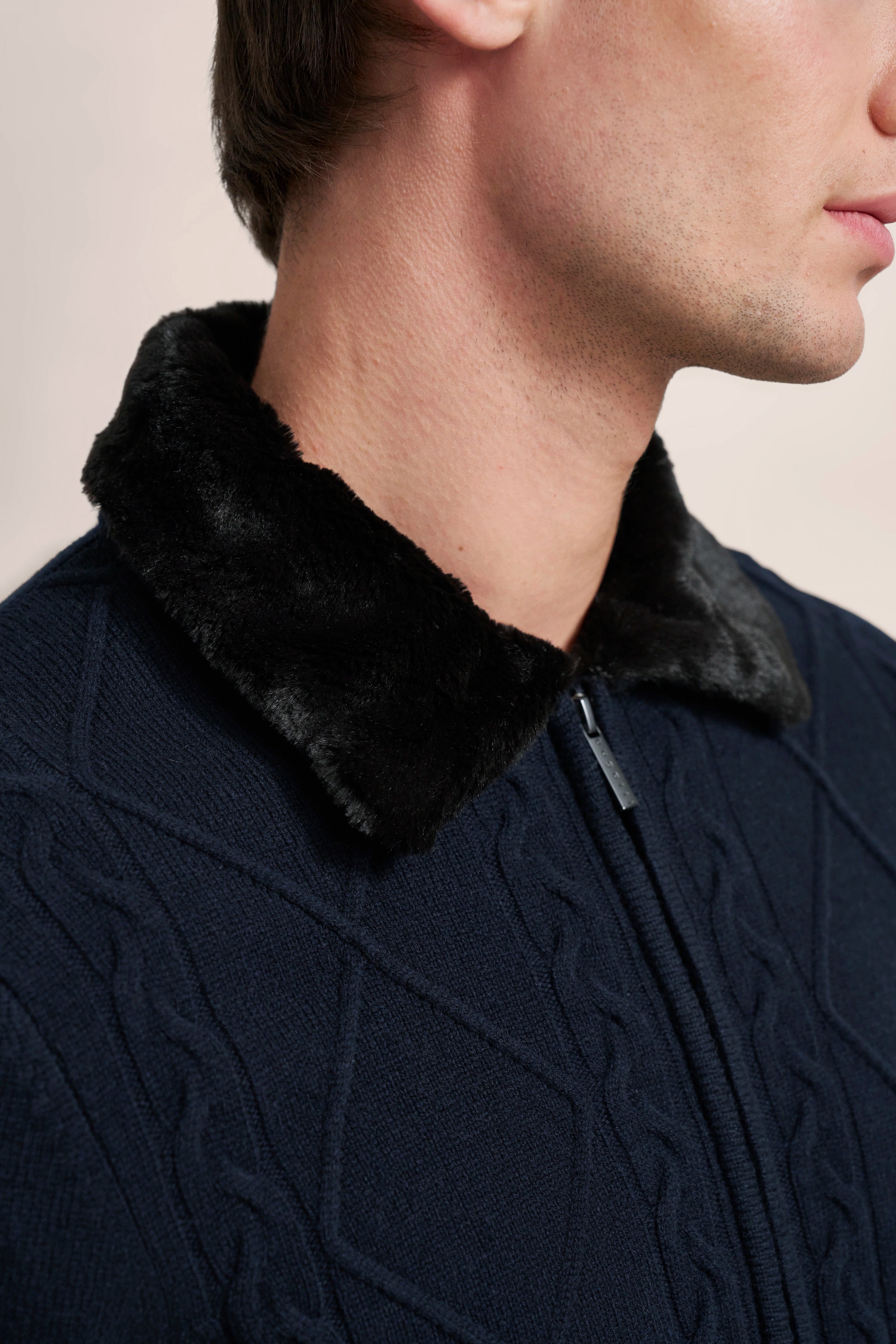 Büstenbild eines Marine-Pullovers mit schwarzem Fellkragen, Zopfmuster.