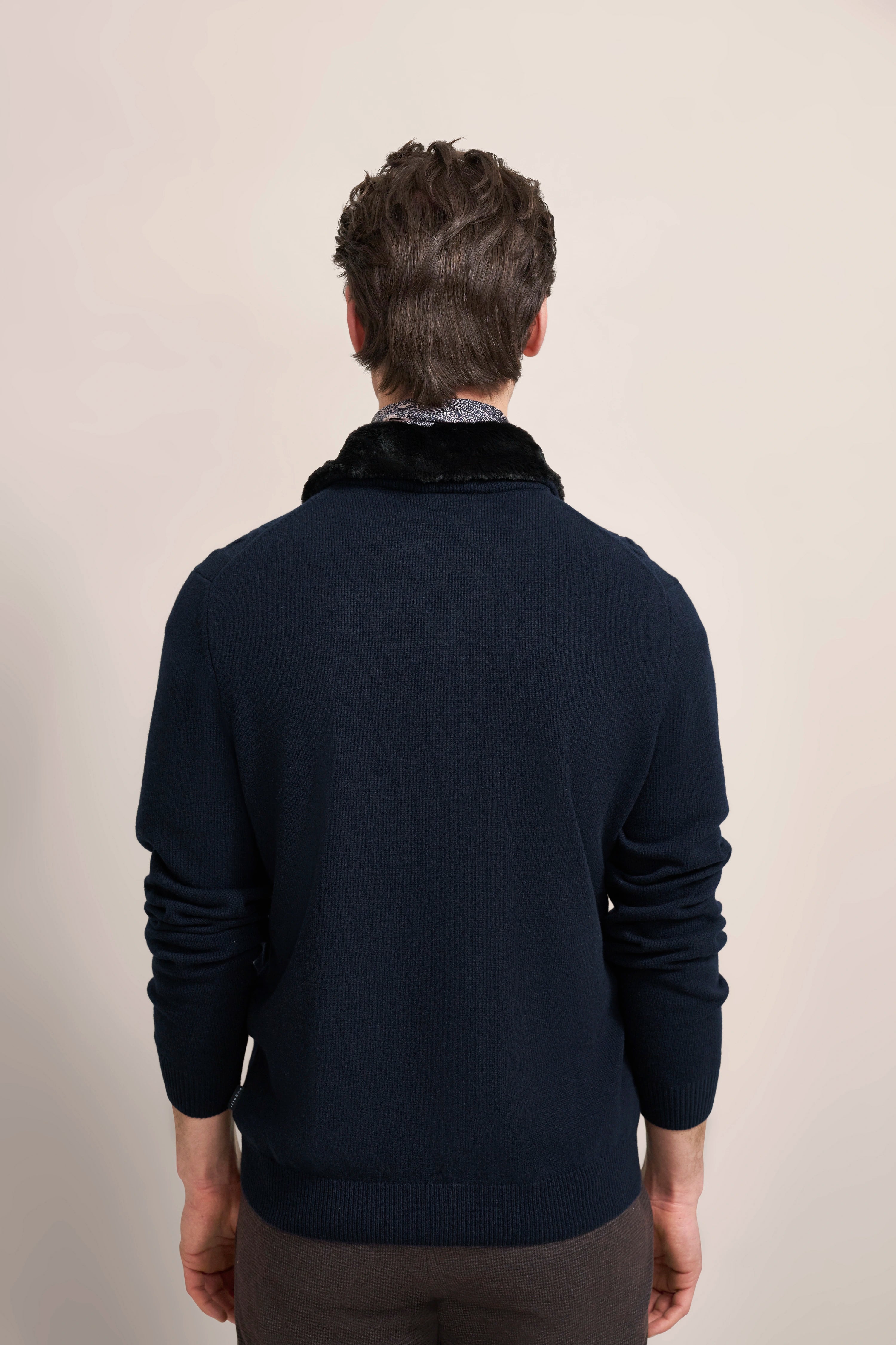 Rückansicht eines Models in dunkelblauem bugatti Pullover mit schwarzem Kragen, legeres Styling.