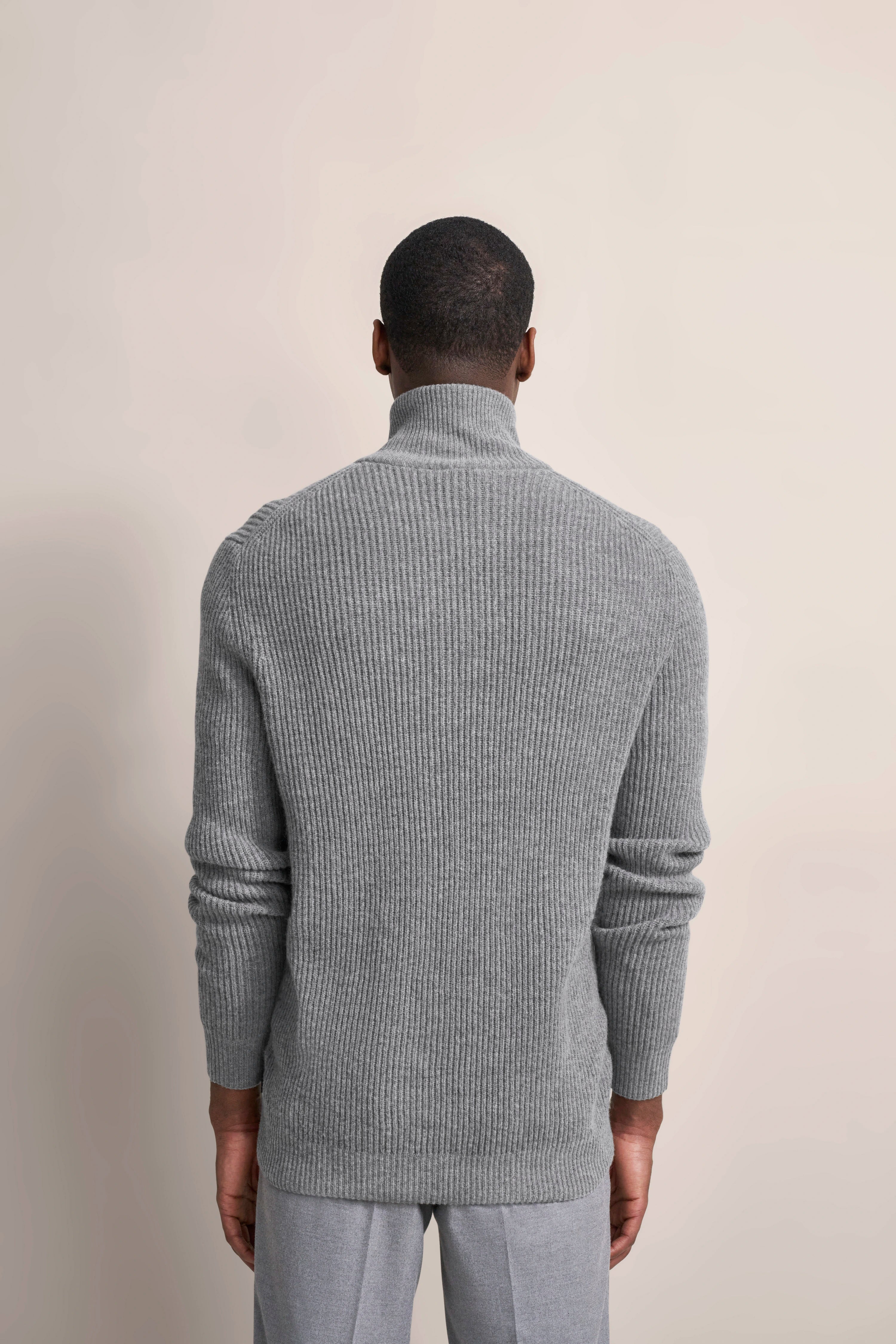 Grauer Rollkragenpullover und graue Hose, Rückansicht, Modelbild, entspannte Haltung.