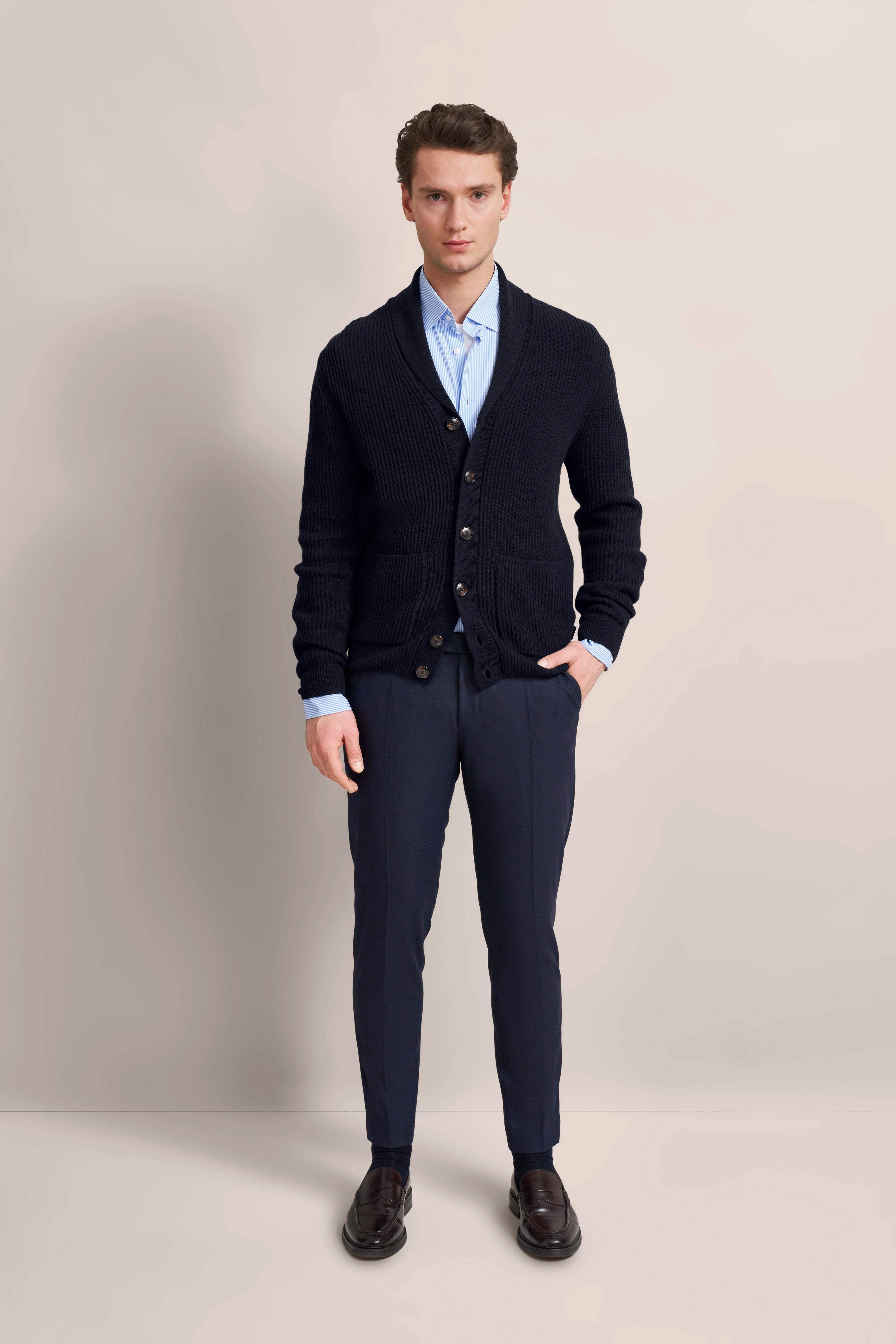 Model im blauen Cardigan und Hemd von bugatti, schwarze Hose, entspannte Pose.