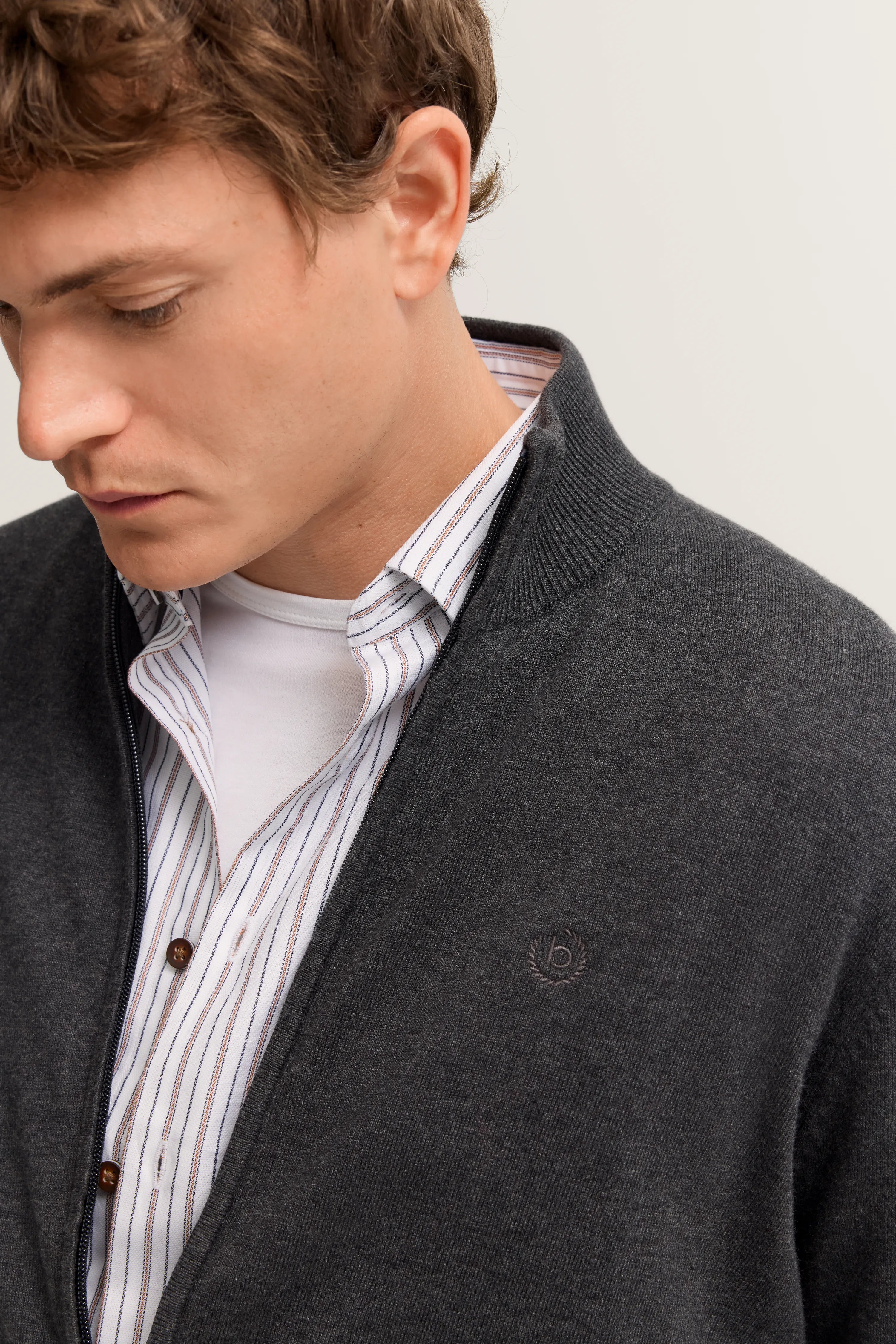 Bugatti Modelbild: Grau Strickjacke, gestreiftes Hemd, Casual-Pose, Stil und Qualität.