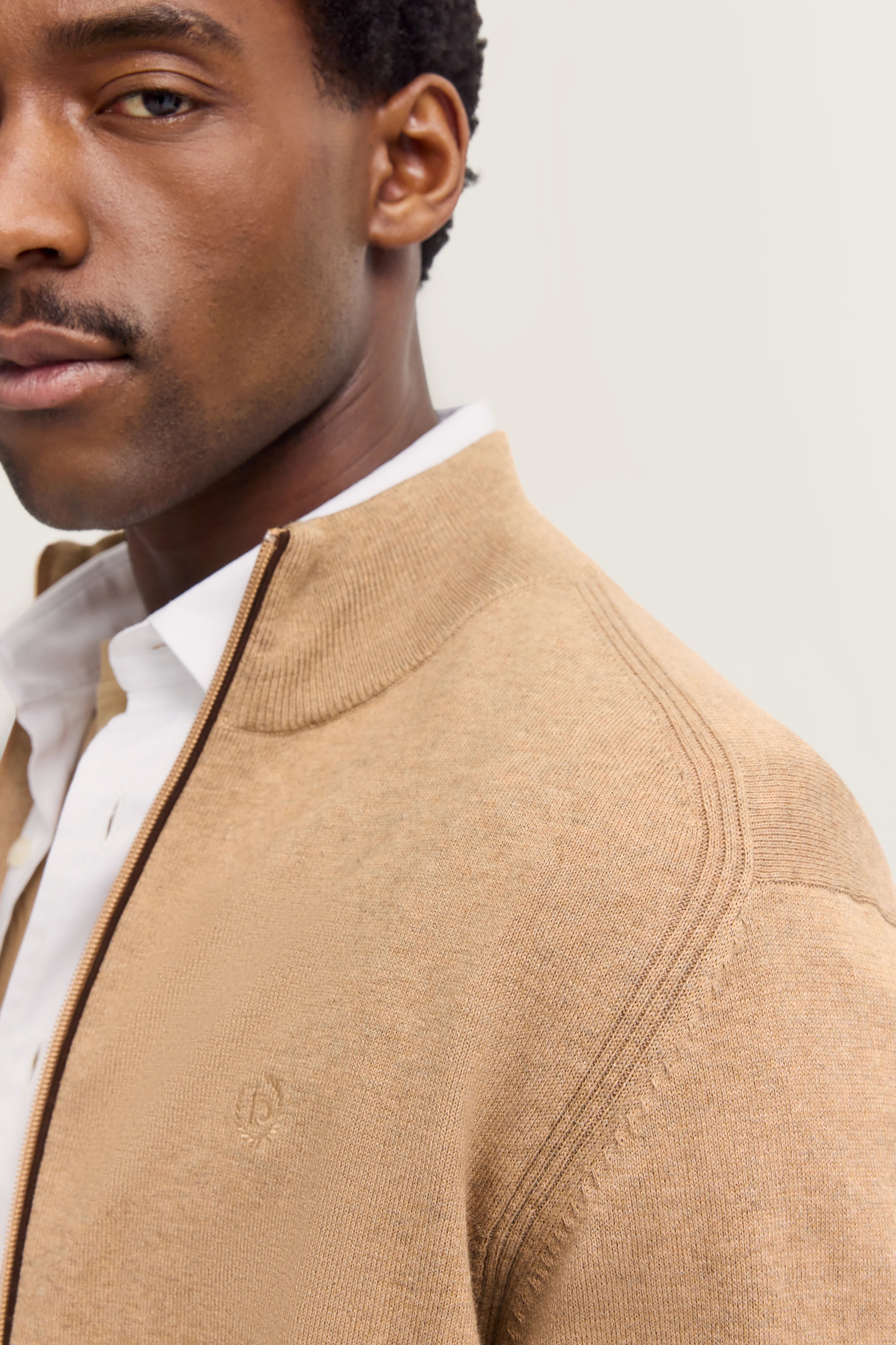 Büstenbild, beige bugatti-Strickjacke über weißem Hemd, eleganter Stil.