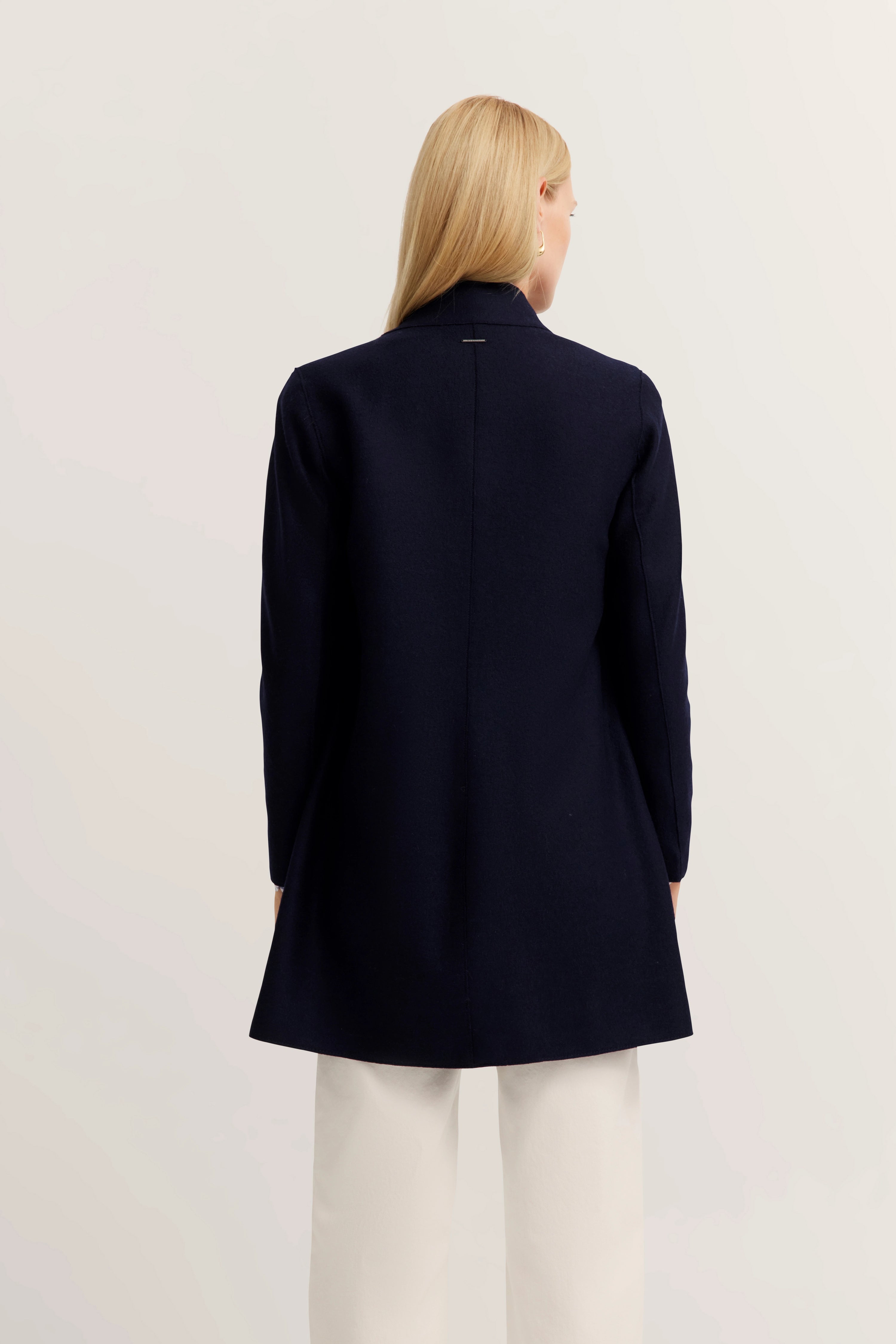 Navy bugatti jas, busteweergave, gecombineerd met witte broek. Elegantie en stijl centraal.