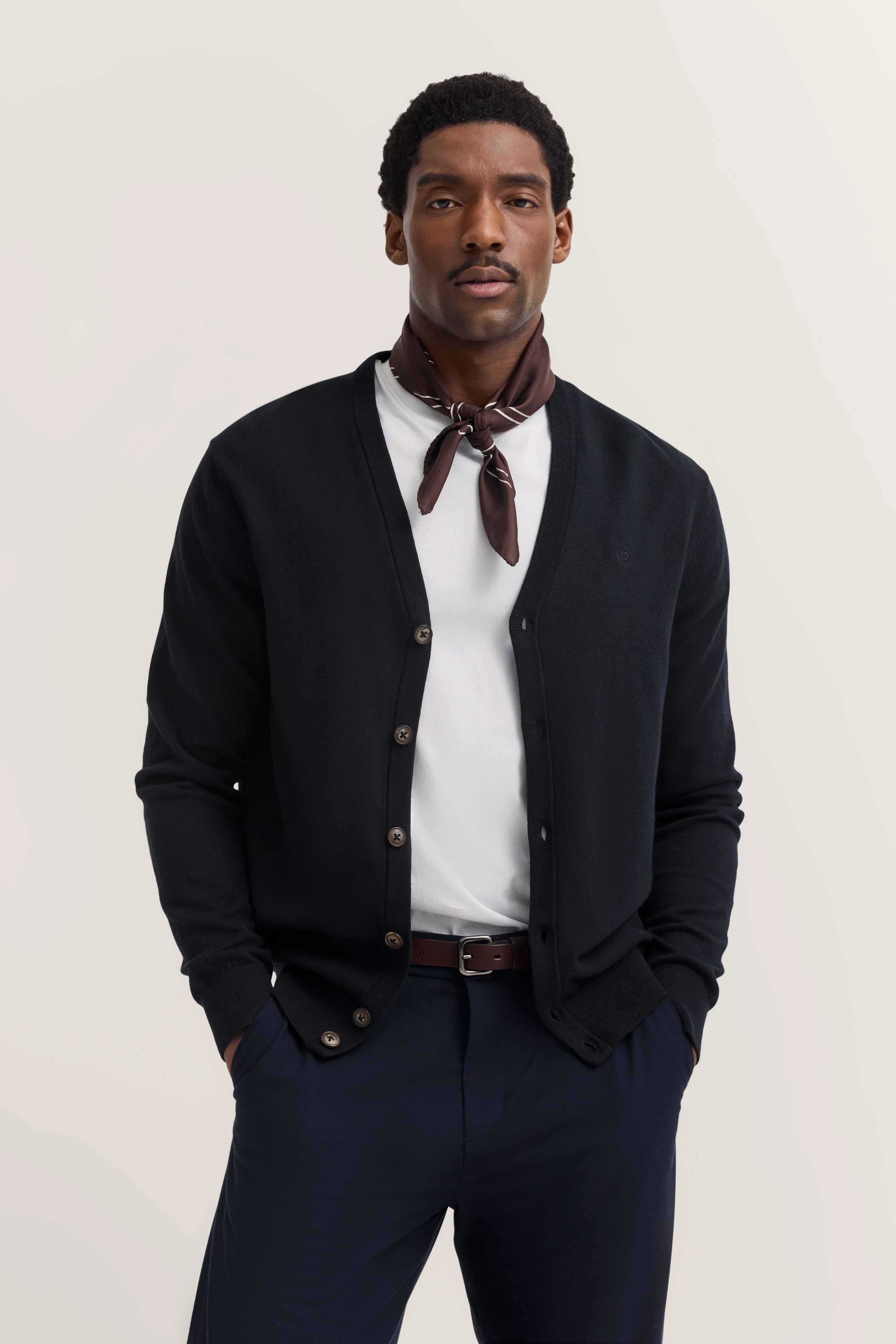 Model in schwarzem Cardigan, weißem Shirt, braunem Halstuch, blaue Hose