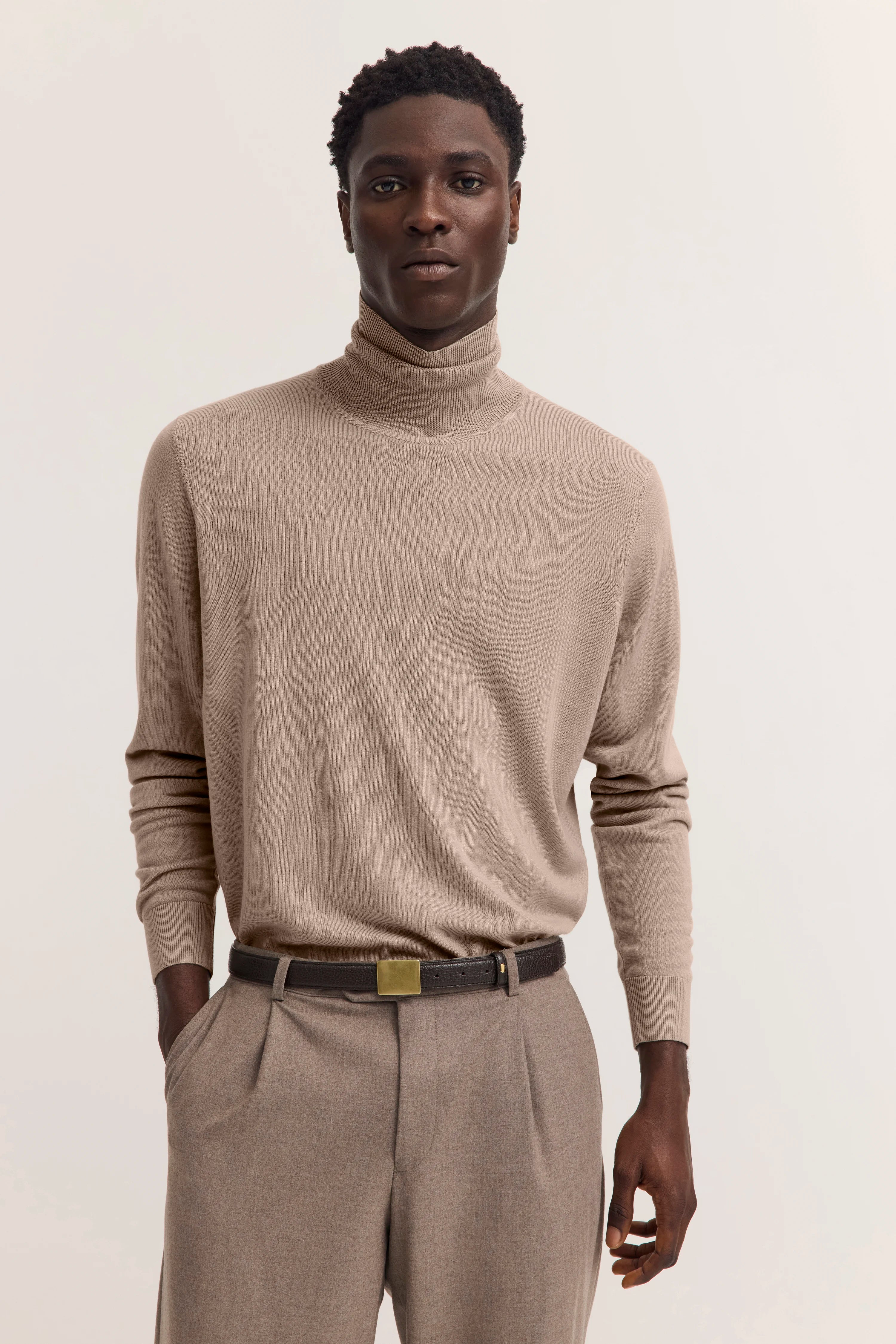 Modelbild: Beiges bugatti Rollkragenshirt, beige Hose, entspannte Pose, stilvoll.