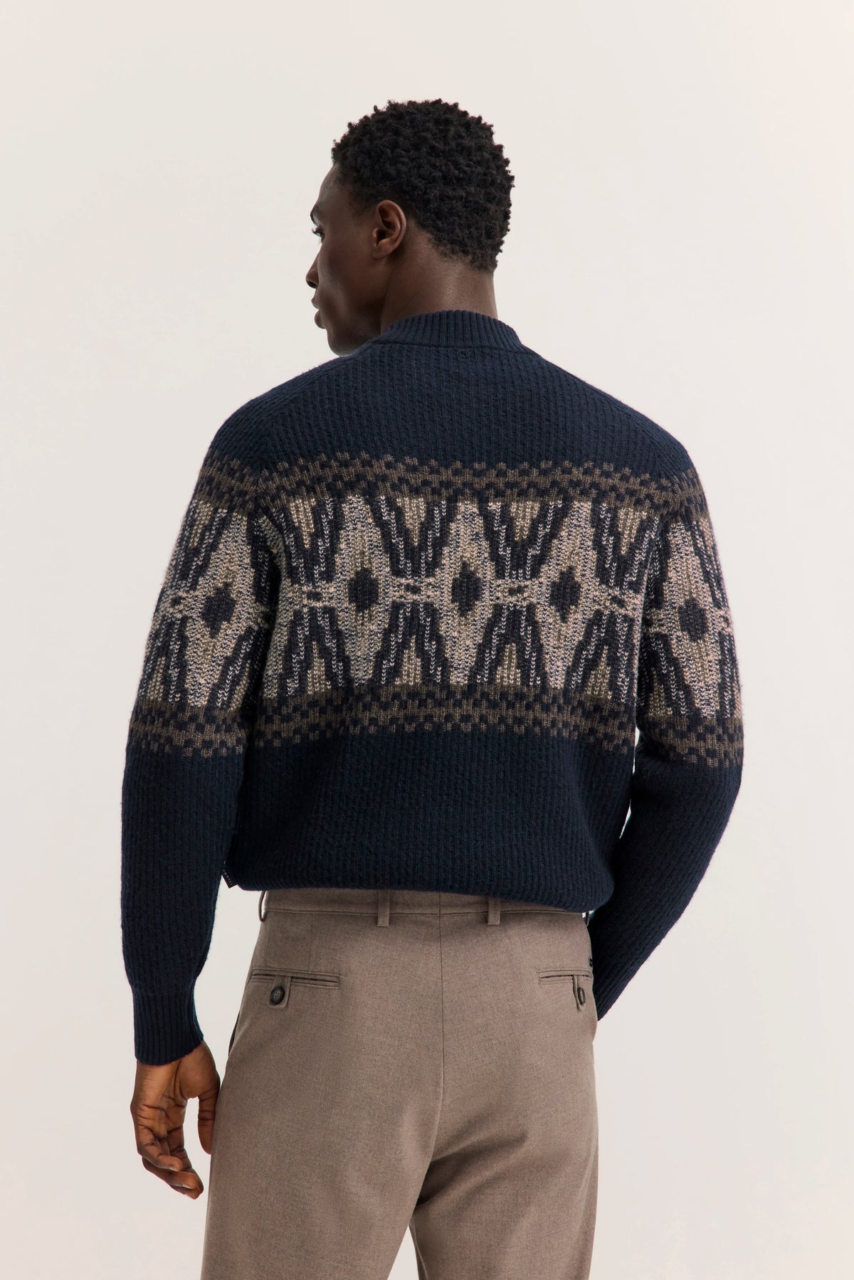 Navy Pullover mit Muster, beige Hose, Model von hinten, entspannter Stand. bugatti Stil.