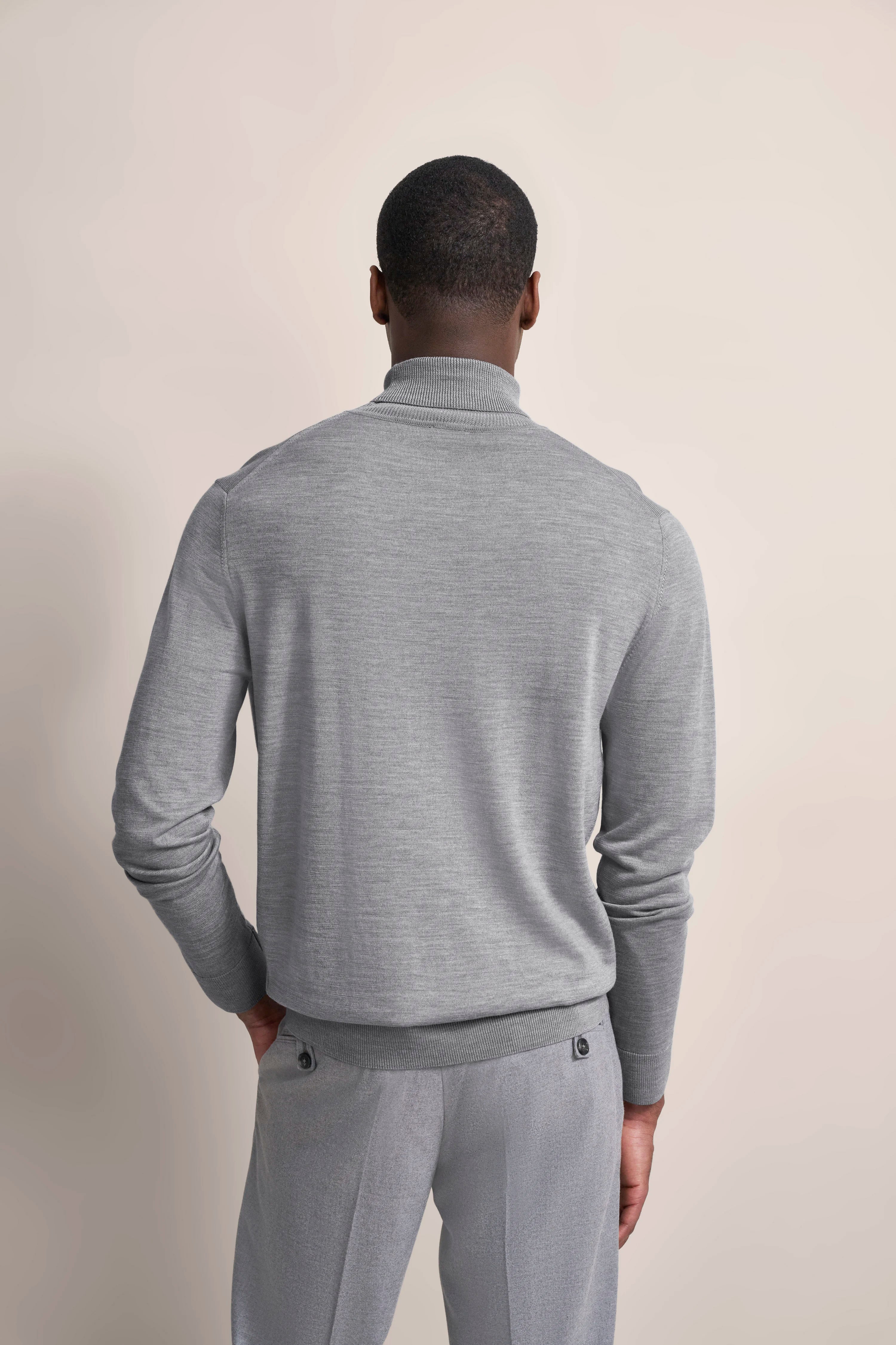 Grauer bugatti Pullover und Hose, Rückansicht, Model mit entspanntem Posing.