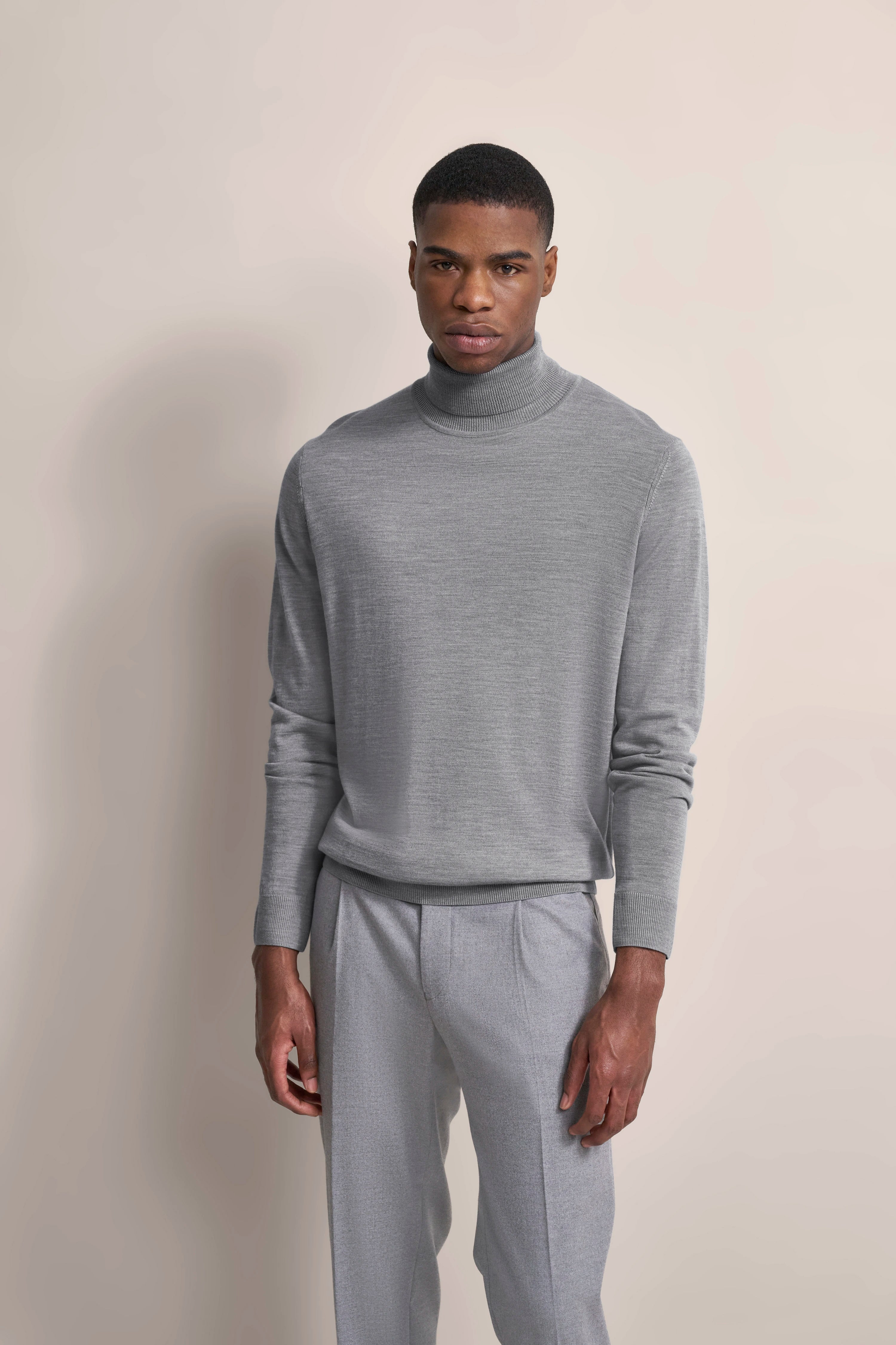 Grauer Rollkragenpullover und Hose, Modelbild, neutrales Posing.