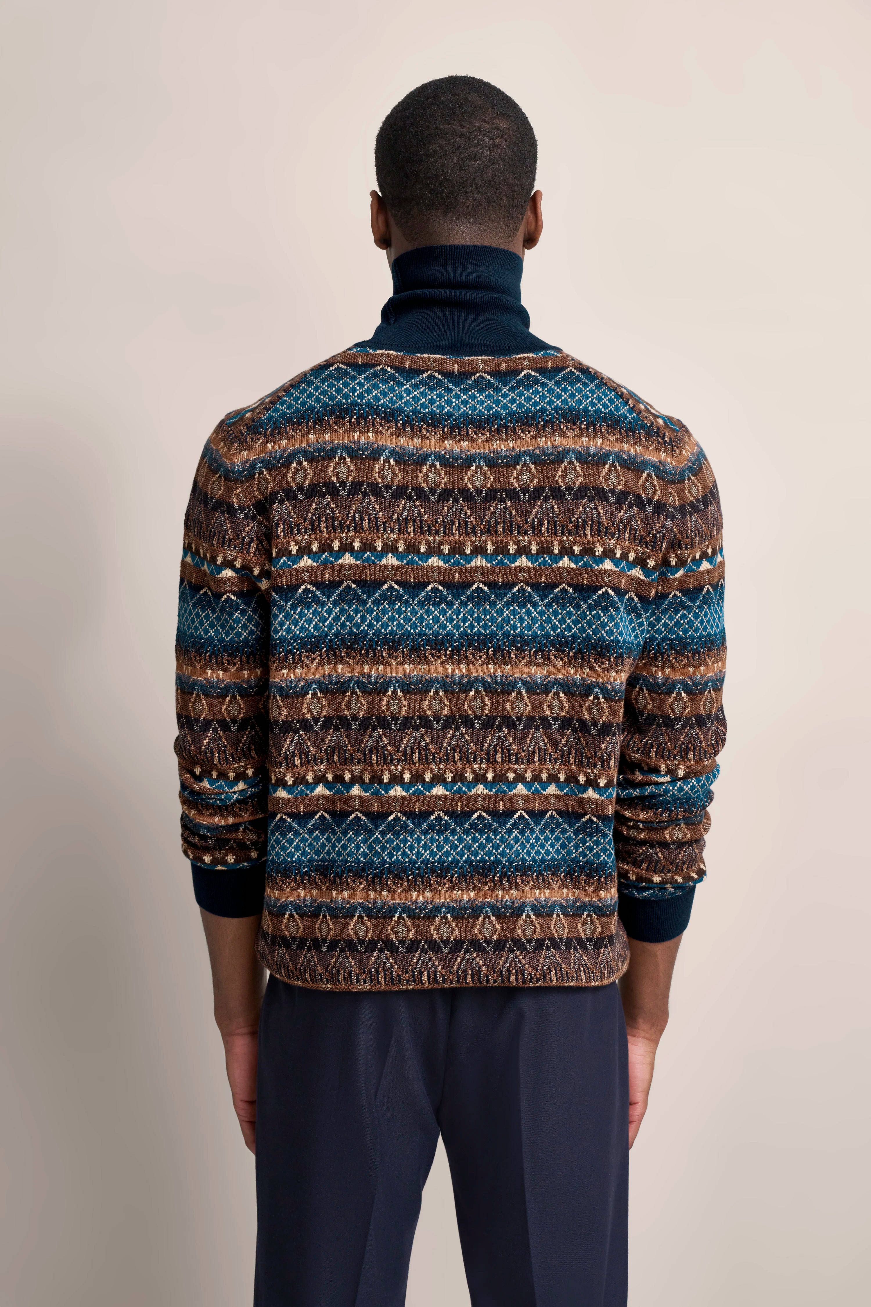 Herrenmodel von hinten mit gemustertem bugatti Pullover, Blau- und Brauntöne, lässig mit Stehkragen.