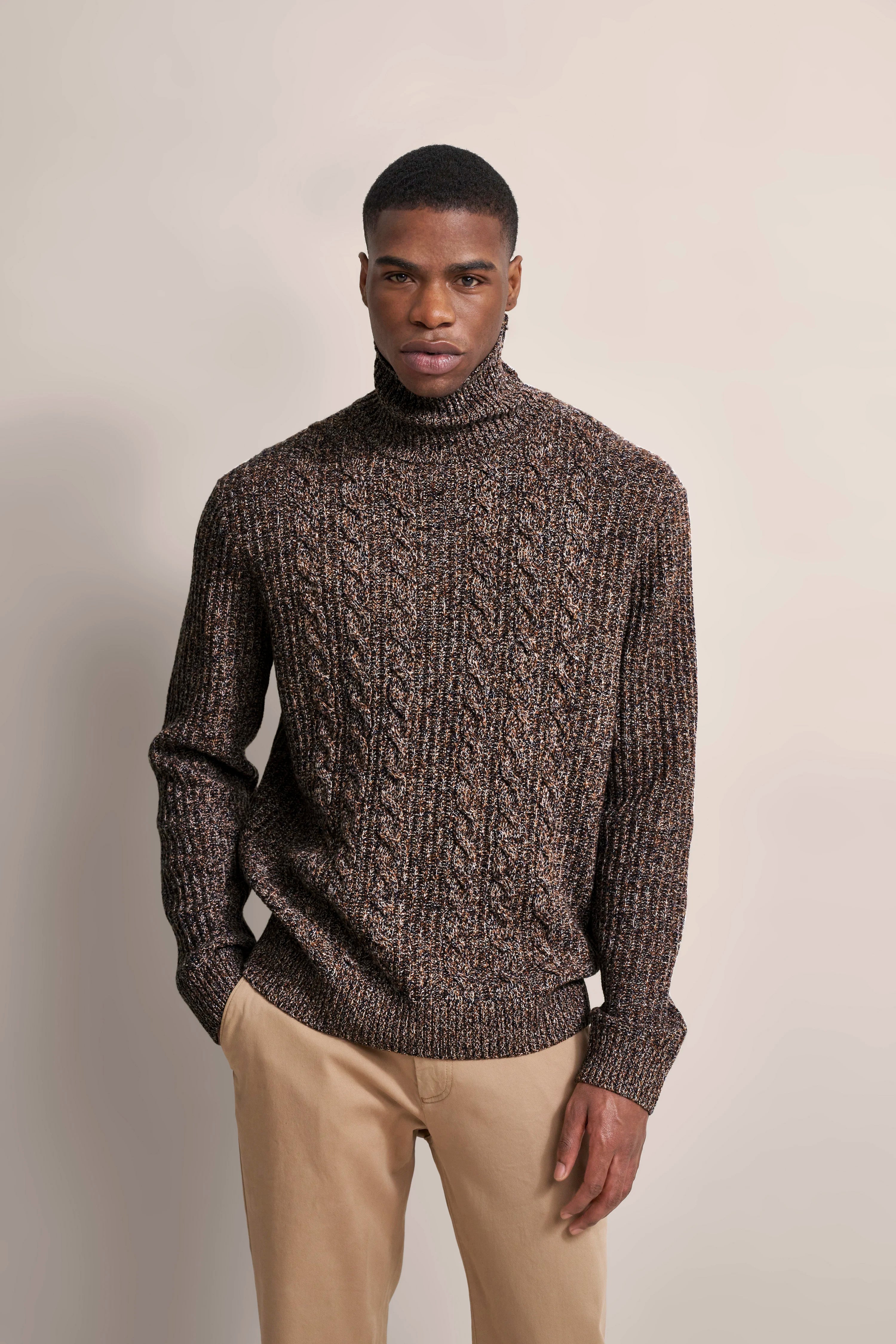 Model in braunem bugatti Rollkragenpullover mit Zopfmuster, beige Hose, lässiger Stand.