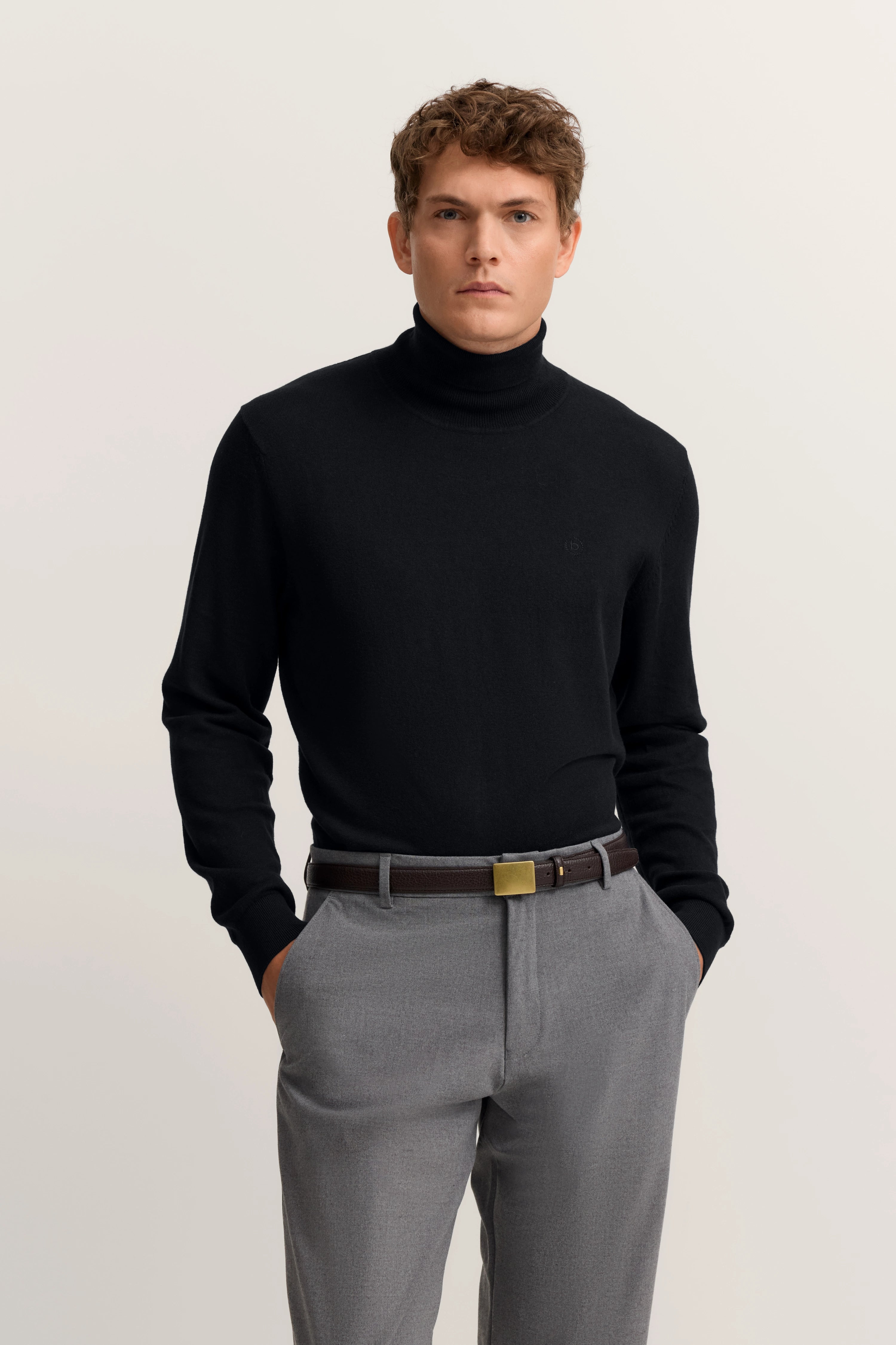 Schwarzer Rollkragenpullover und graue Hose, Modelbild, entspannte Pose.