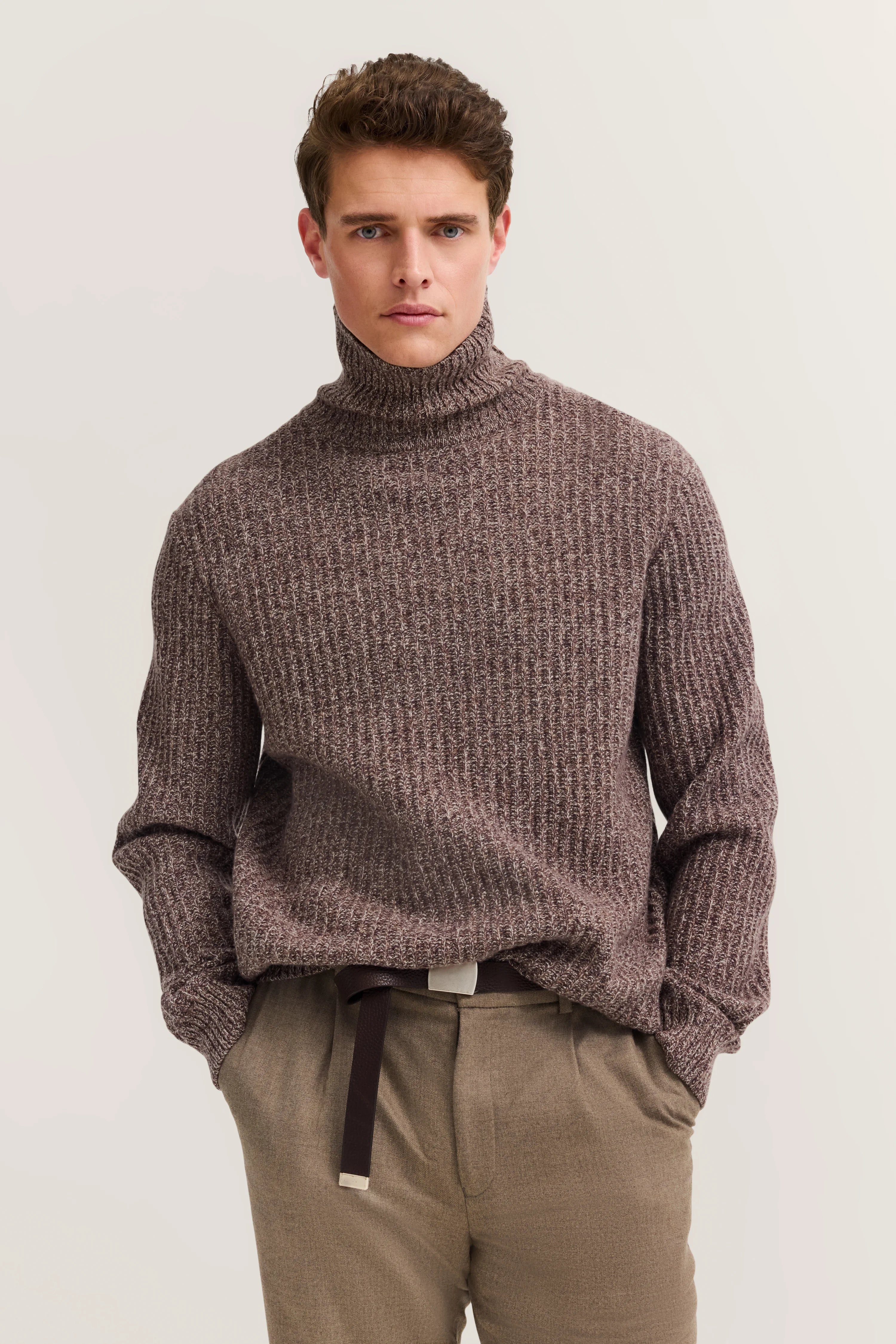 Brauner Rollkragenpullover und beige Hose von bugatti, Modelbild mit lässigem Stand.