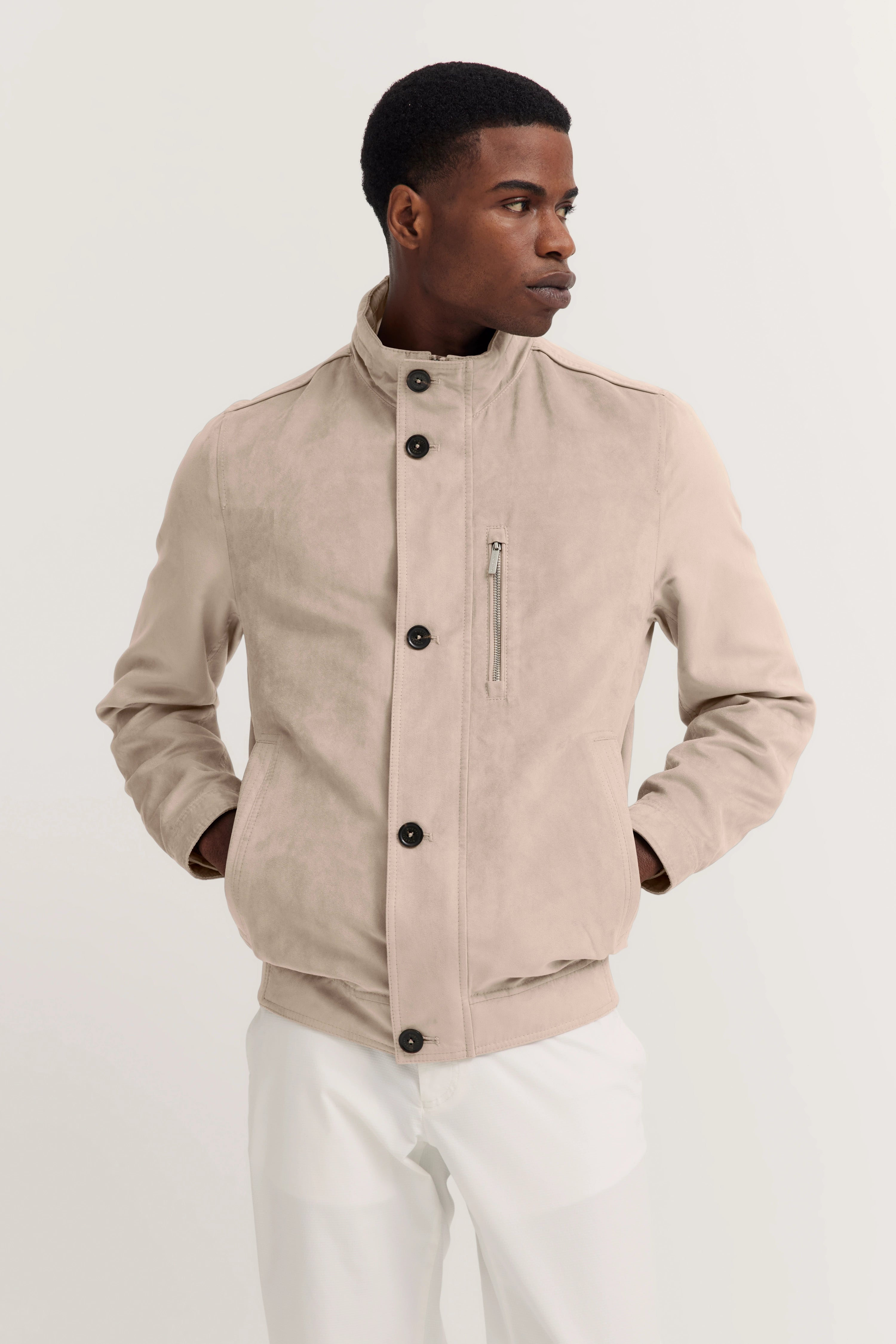 Beige bugatti jas en witte broek, modelpose, stijlvol en elegant.