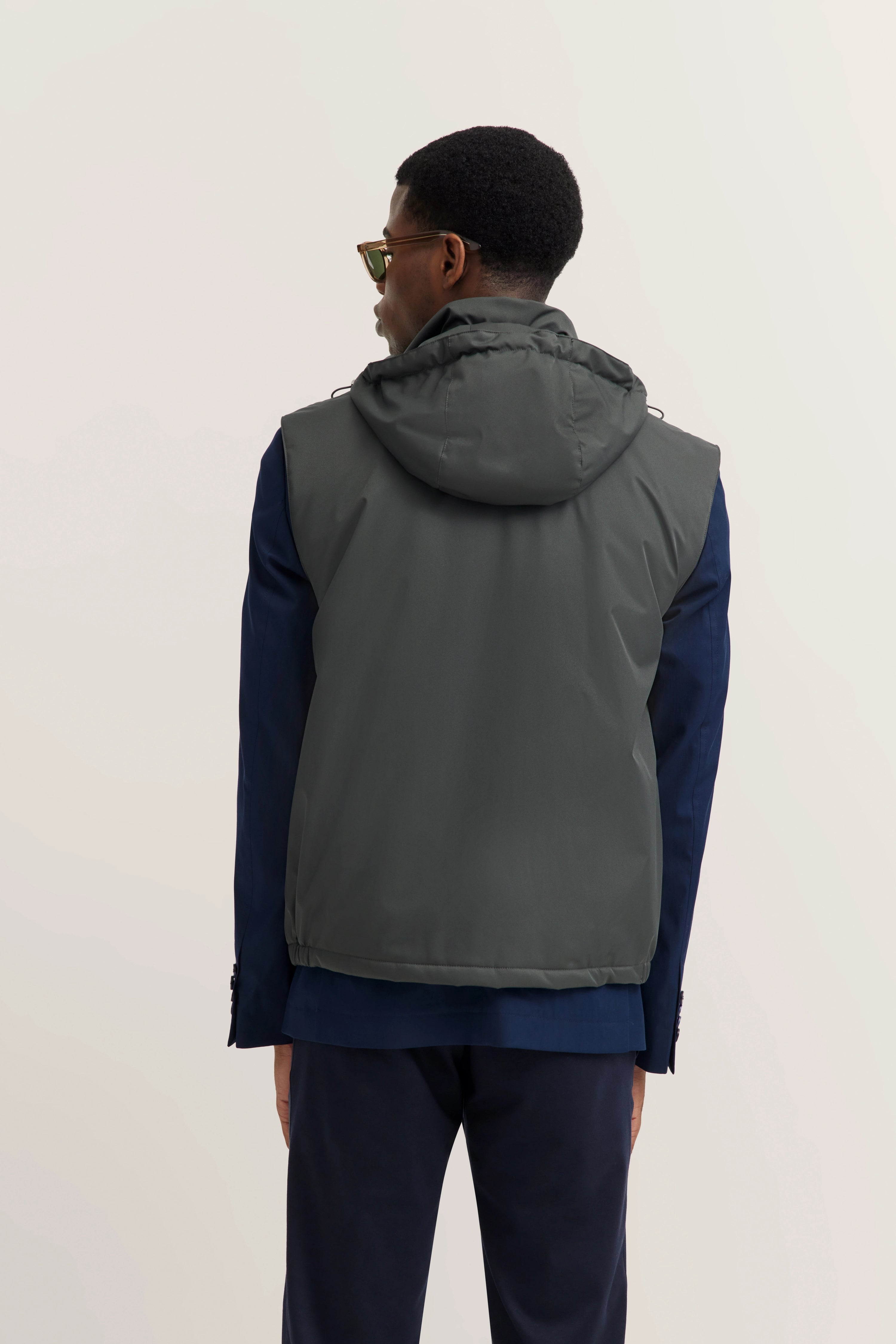 Modelbeeld: Man in donkergrijs vest, blauw pak. Rugaanzicht, ontspannen houding.