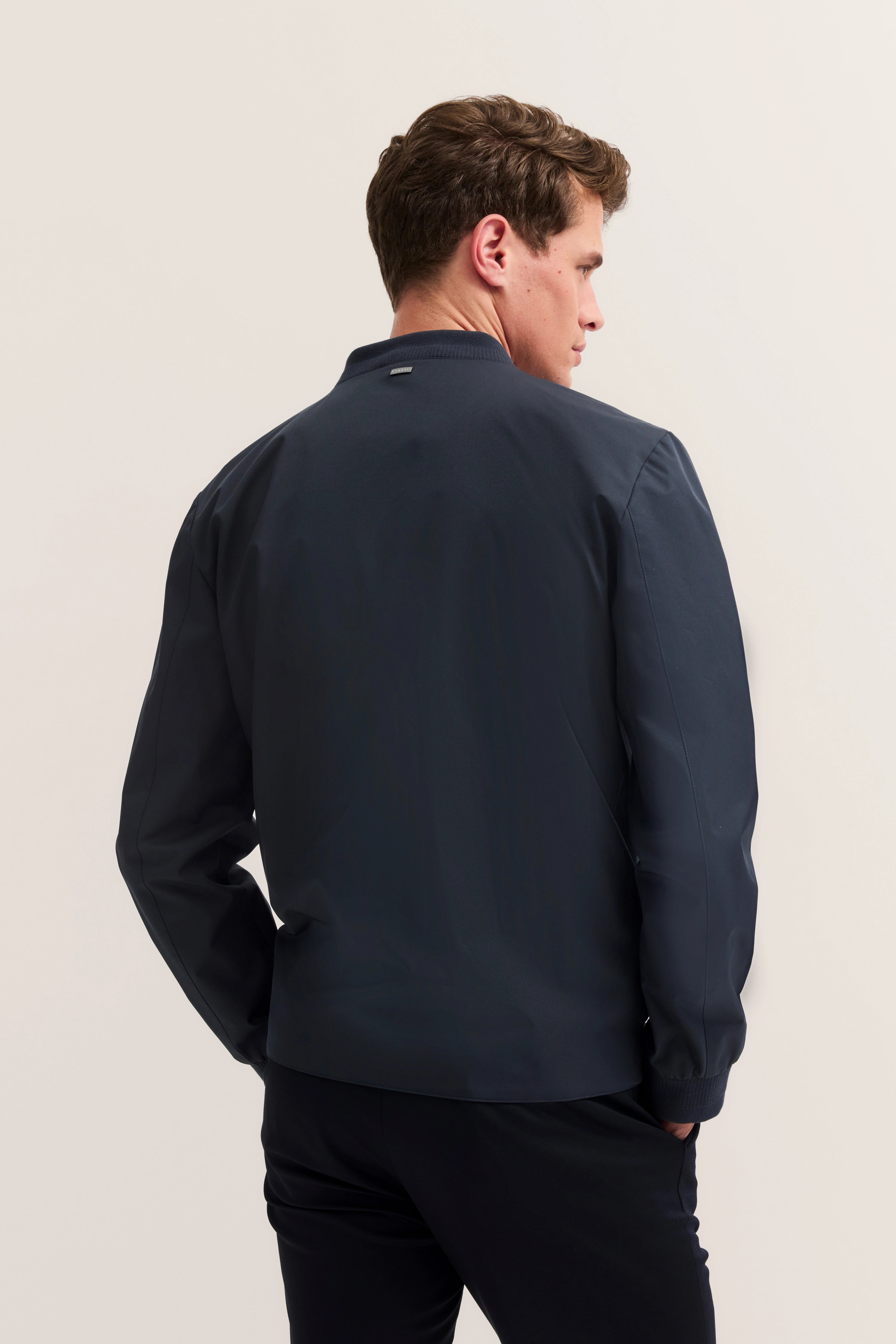 Modelbild, dunkelblaue bugatti-Jacke, Rückenansicht, entspannte Pose.