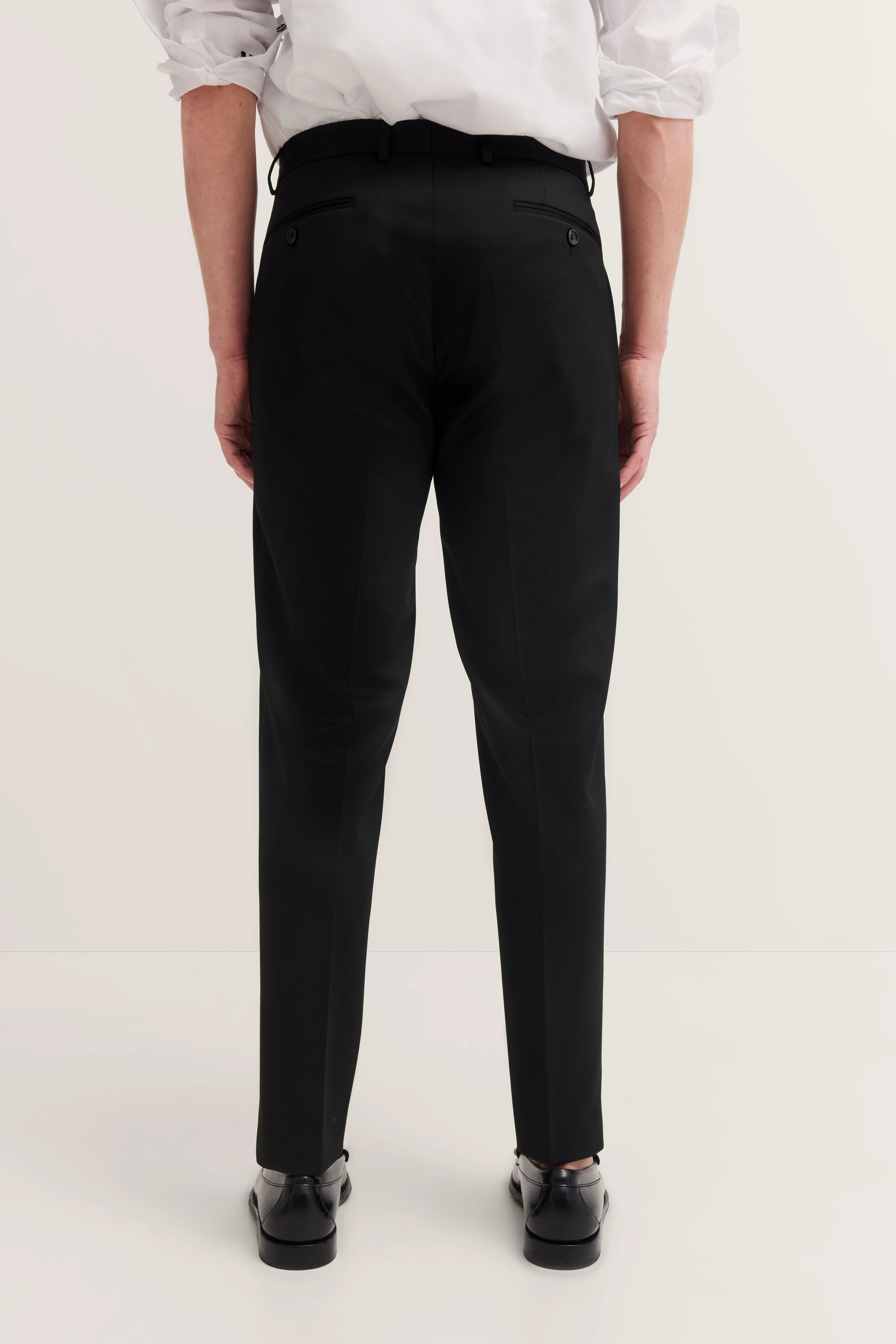 bugatti black pants, white shirt, model image, back view, relaxed pose.