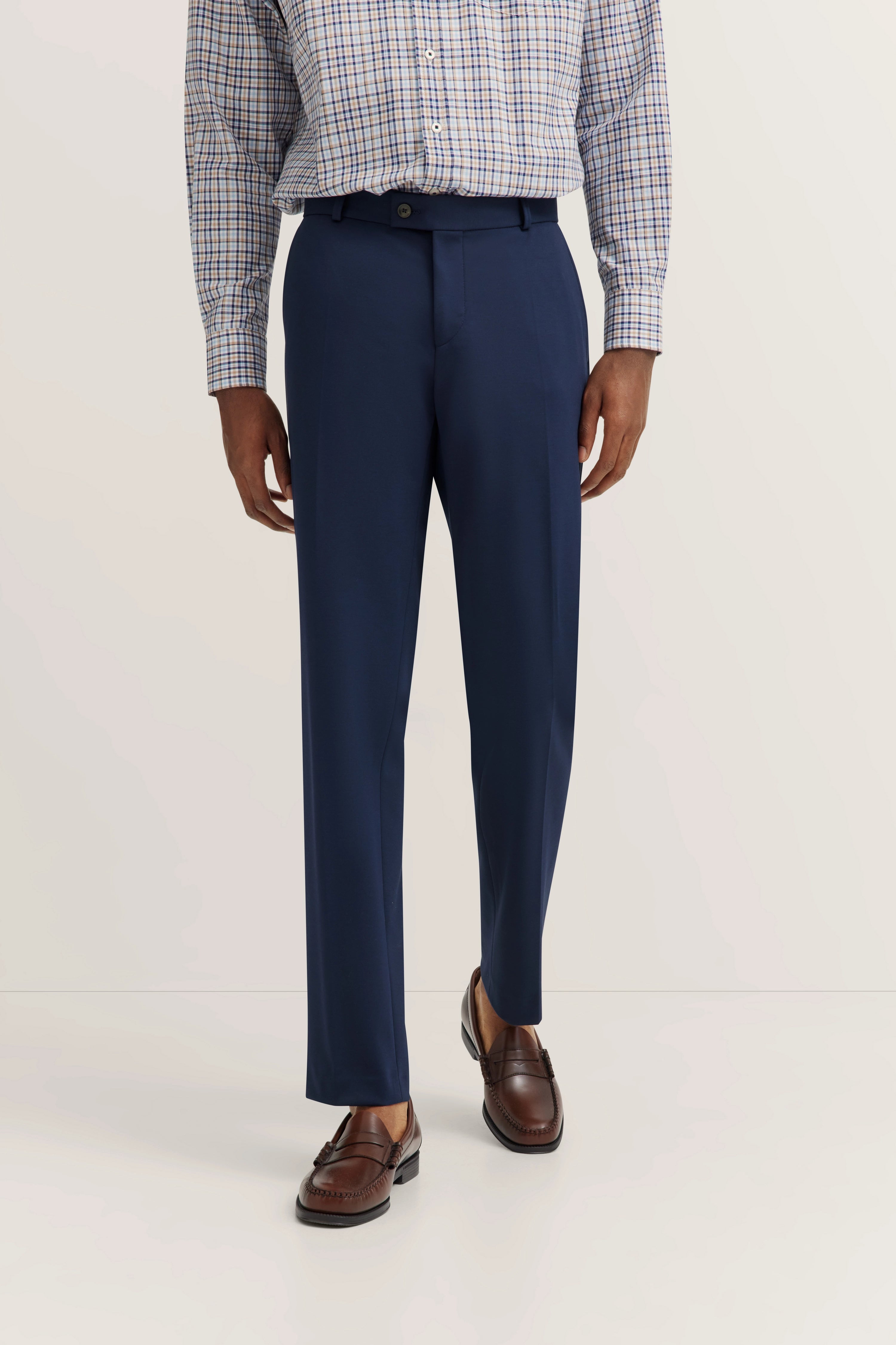 bugatti model: Blue checked shirt, dark blue pants, casual pose, brown loafers.