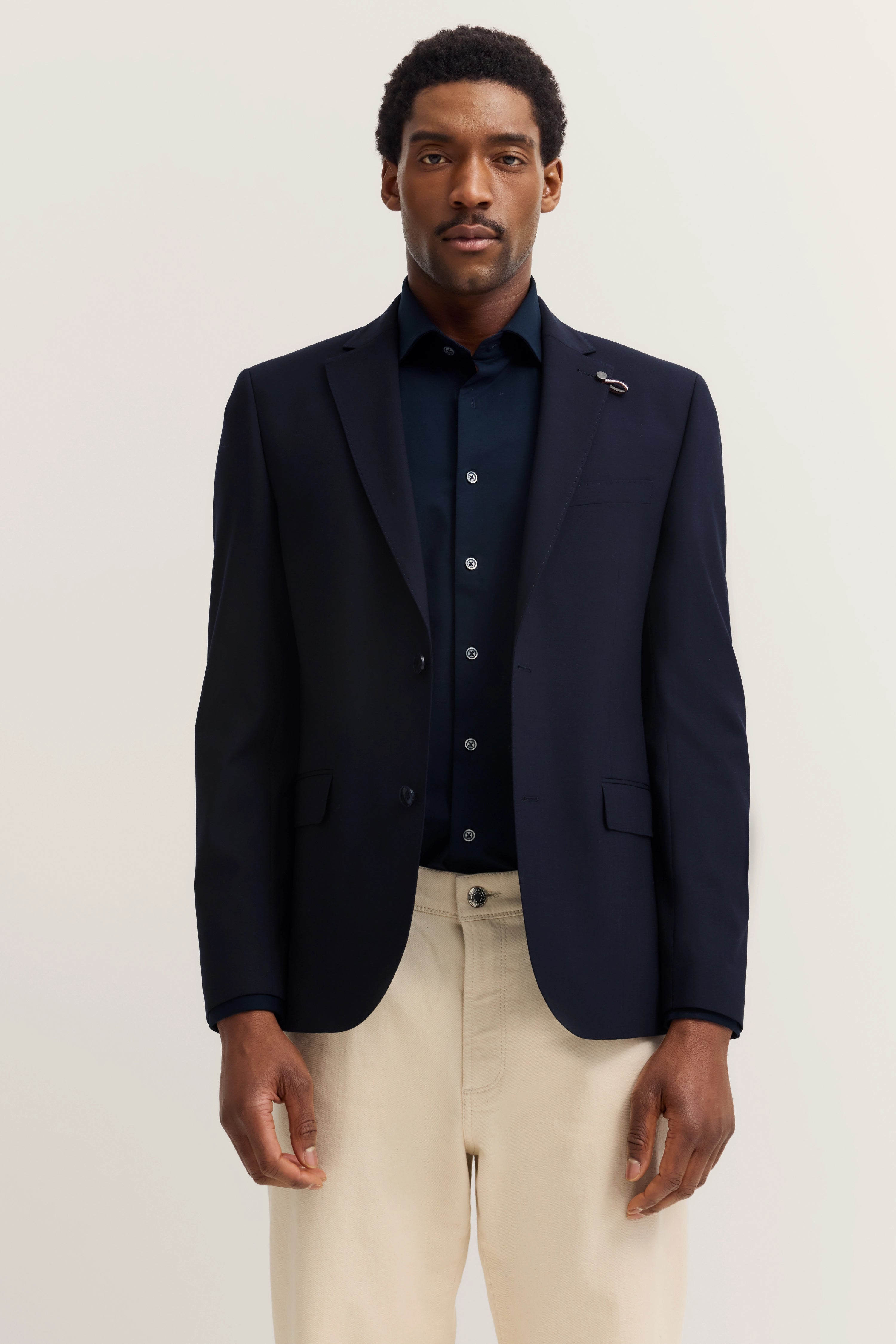 Navy Blazer und Hemd, beige Hose, aufrecht stehend