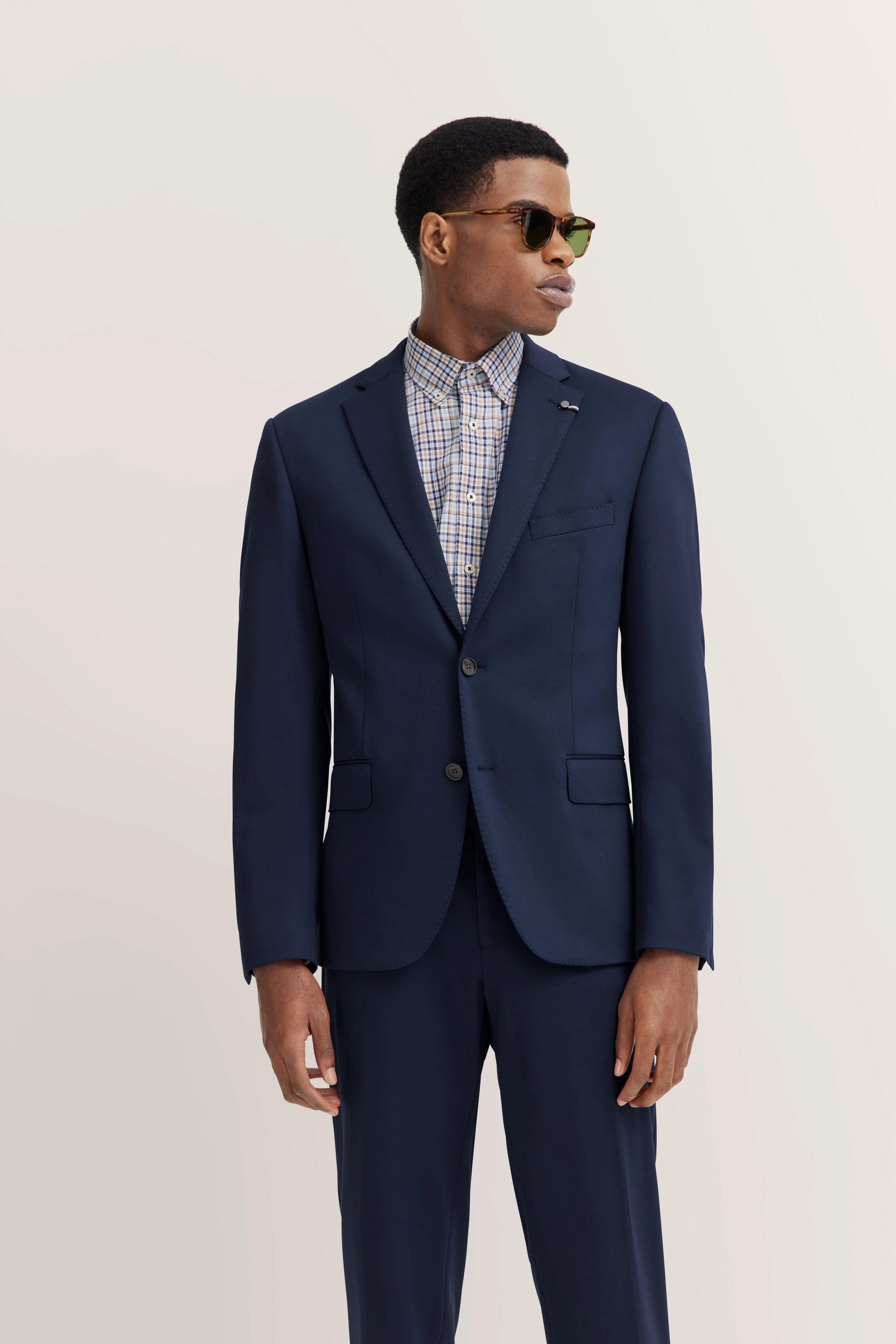 Navy suit with checkered shirt, model posing sideways, bugatti style.