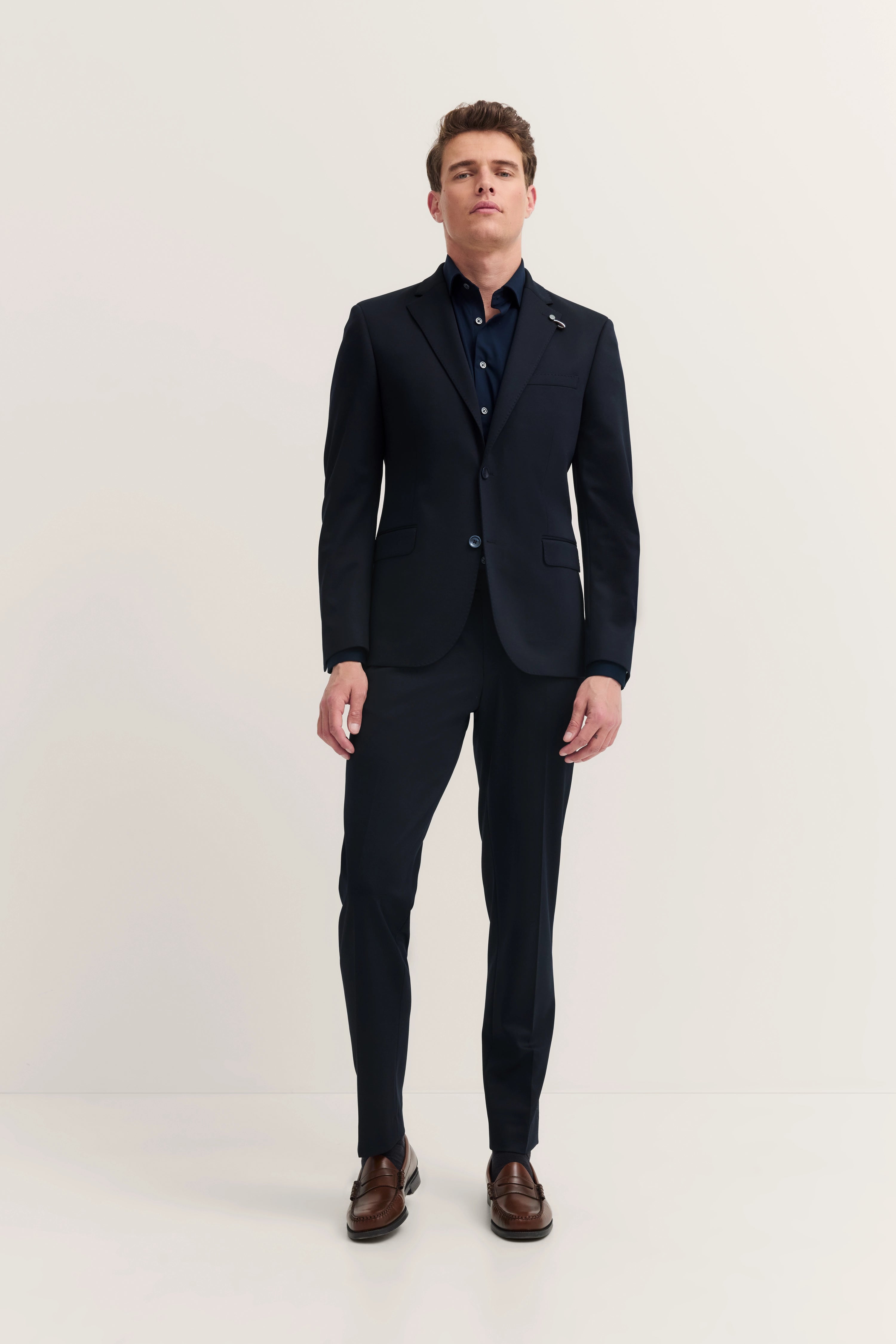 bugatti model in dark blue suit, casual pose, brown loafers, stylish and timeless.