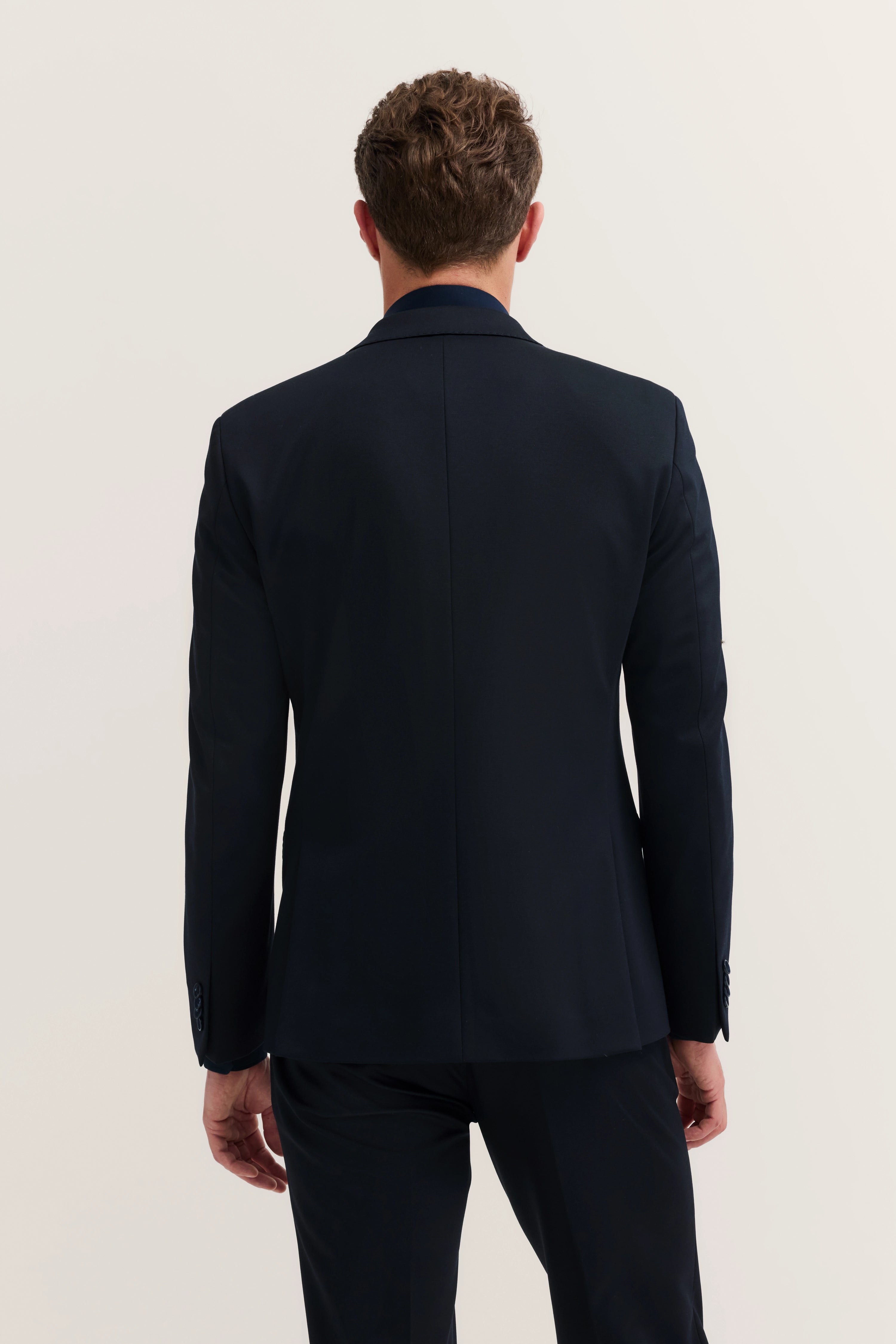 Dark blue bugatti suit from back, model pose, straight stance.