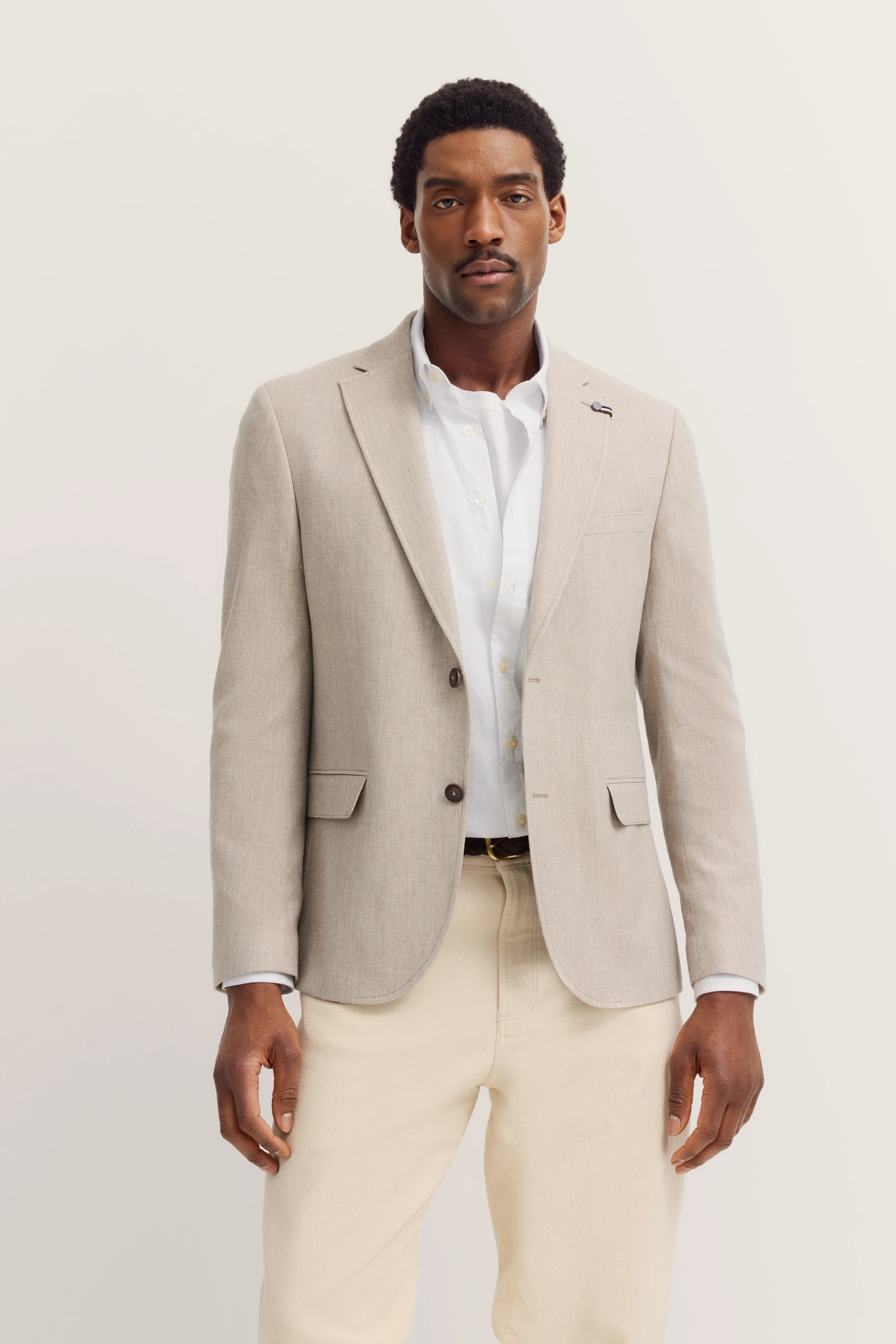 Beige bugatti blazer with white shirt and beige trousers, model in relaxed pose.