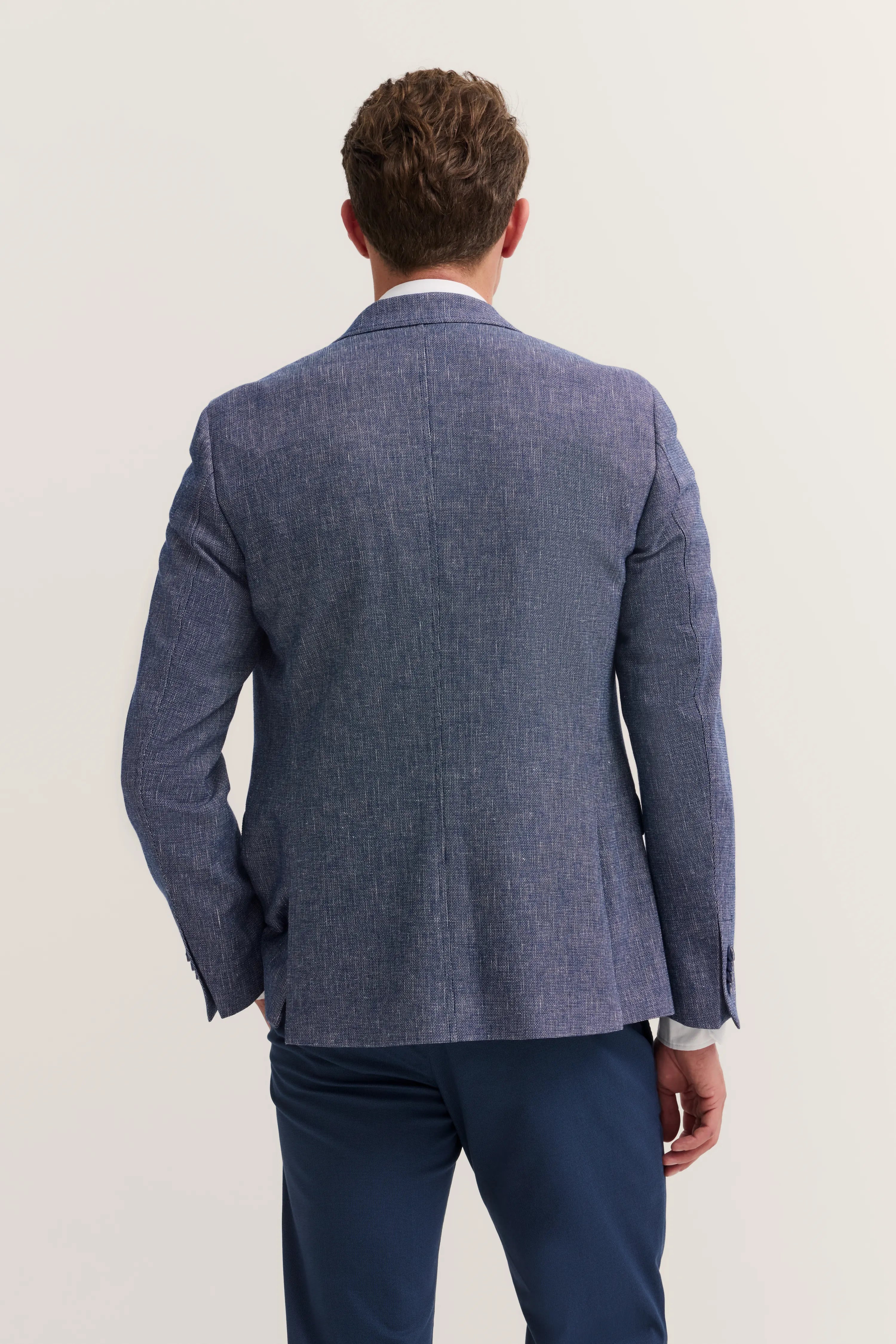 Blue bugatti blazer on model, back view, paired with dark blue trousers.