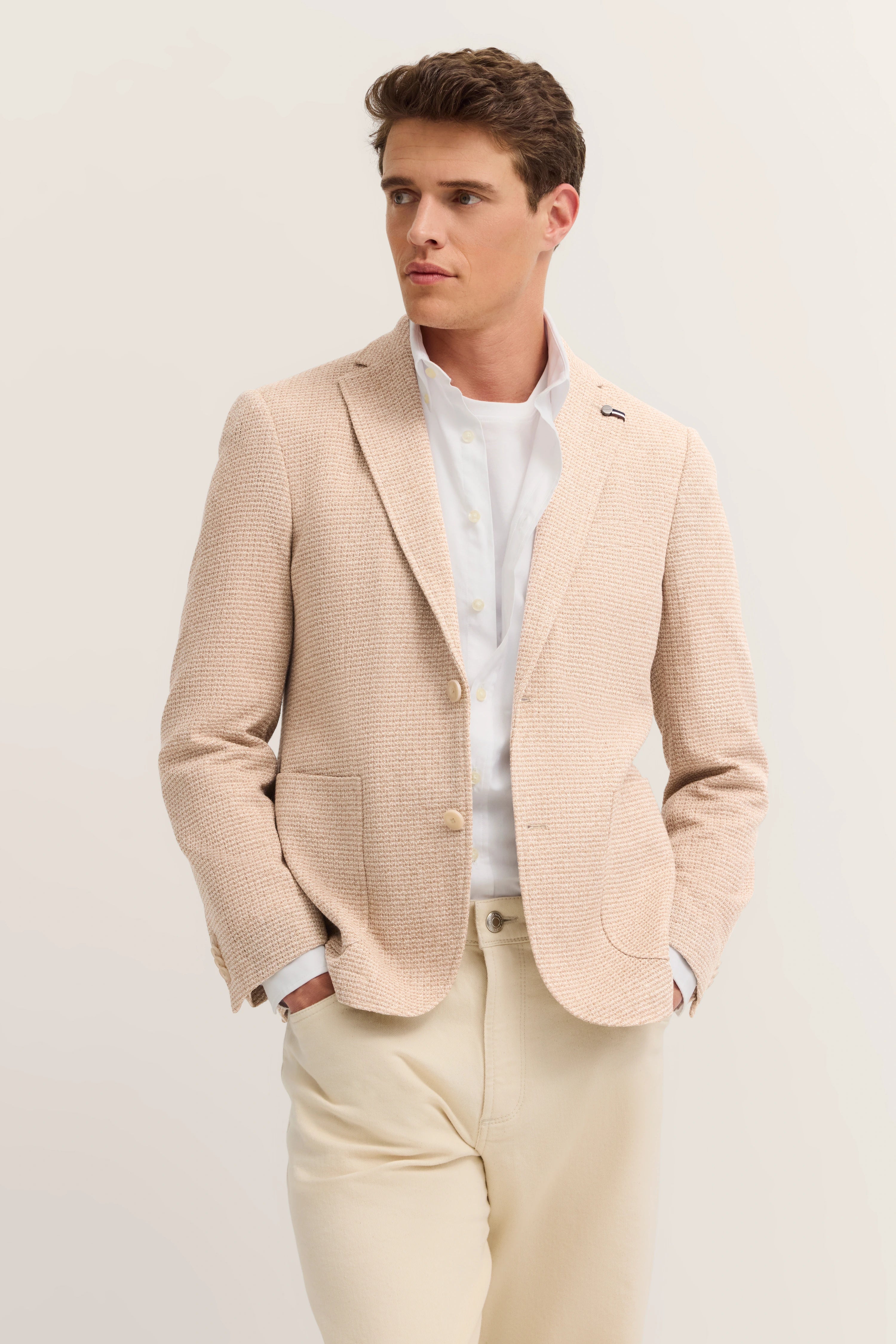 Beige bugatti blazer, white shirt, cream trousers, model pose, timeless elegance.