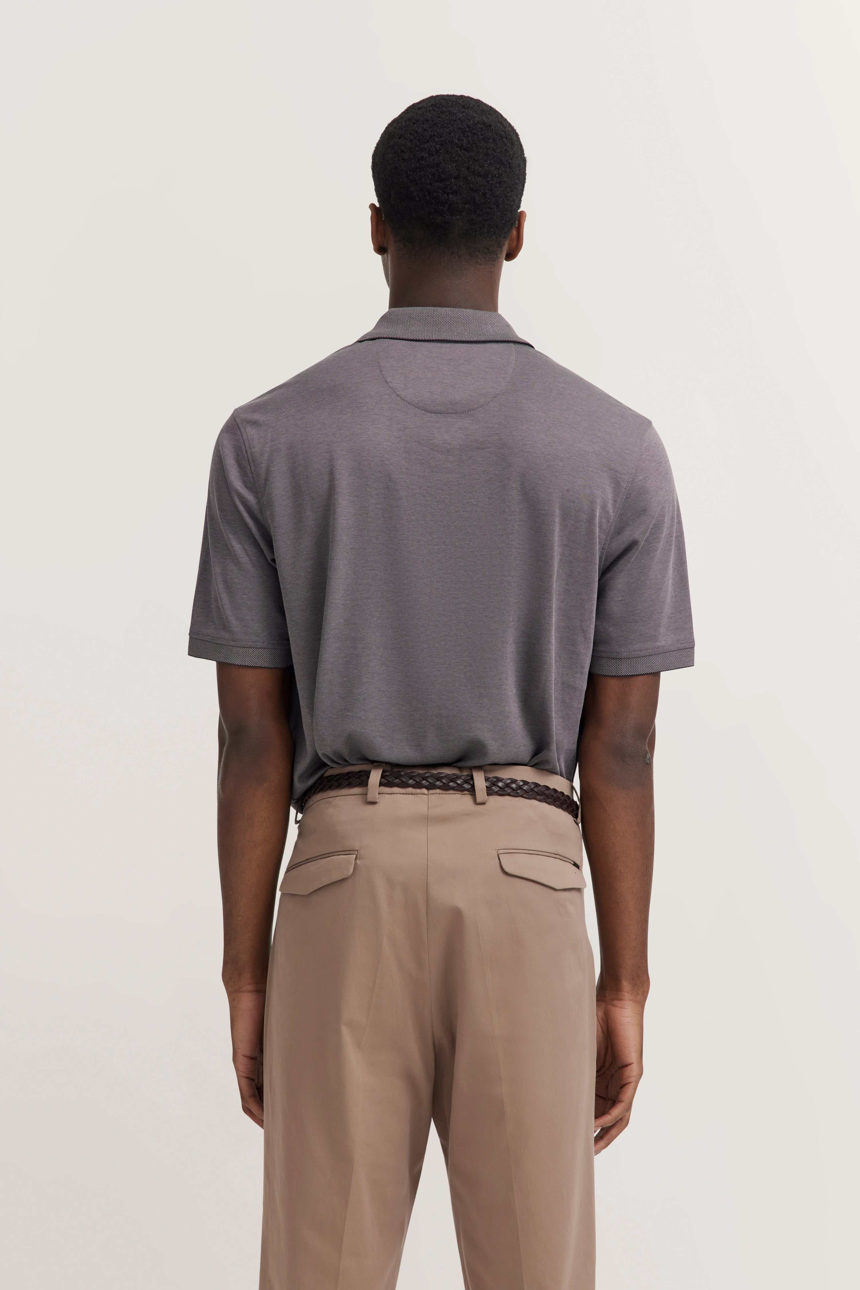 Model in gray polo and beige pants, back view, relaxed pose.